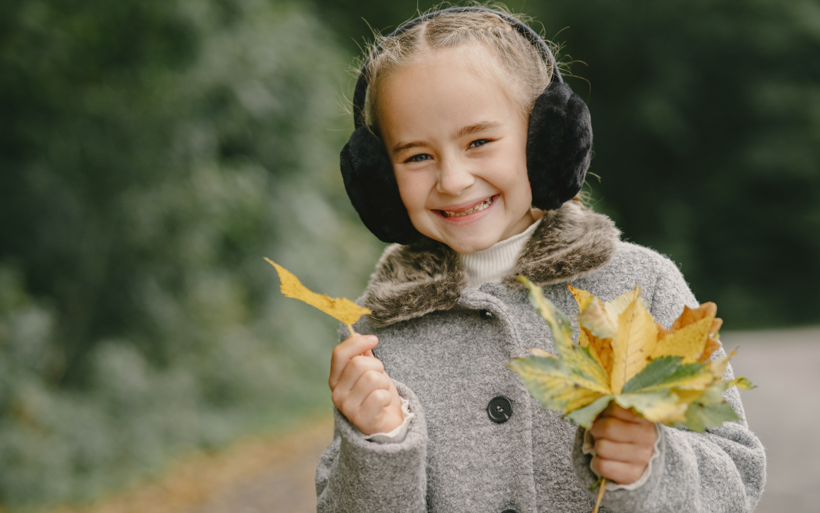 Улыбающаяся девочка с опавшими листьями в руках