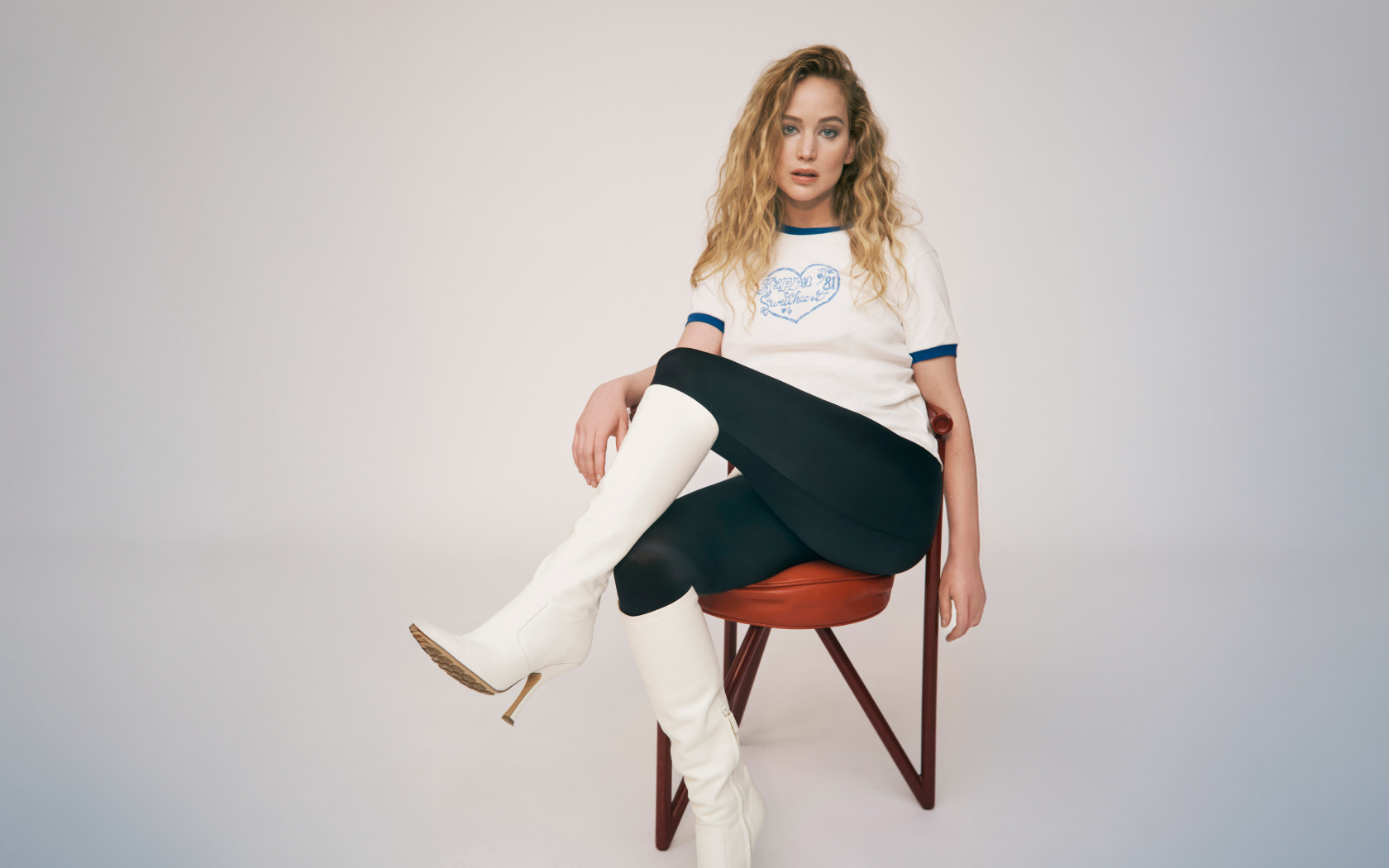 Актриса Дженнифер Лоуренс сидит на стуле на сером фоне