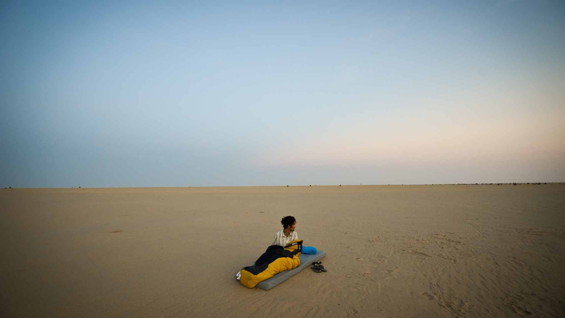 Мужчина на матрасе на пляже