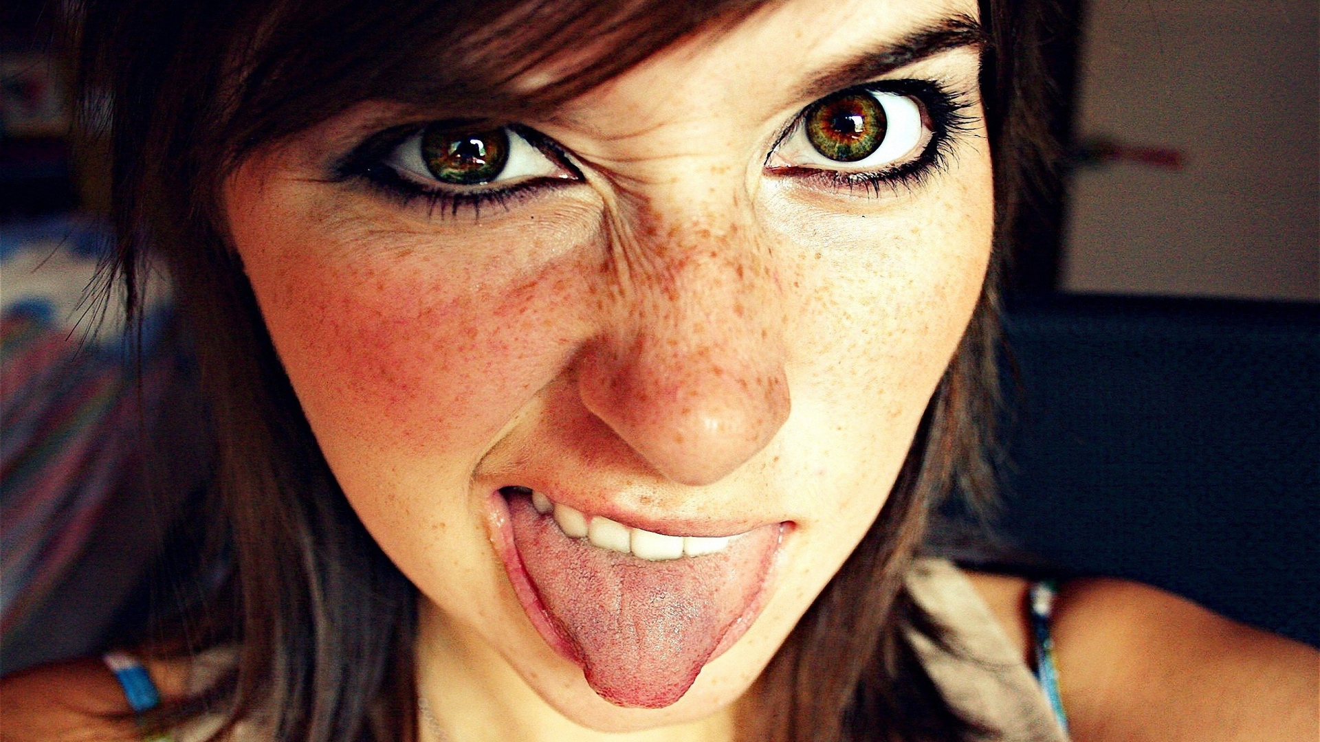 Девушка с веснушками показывает язык