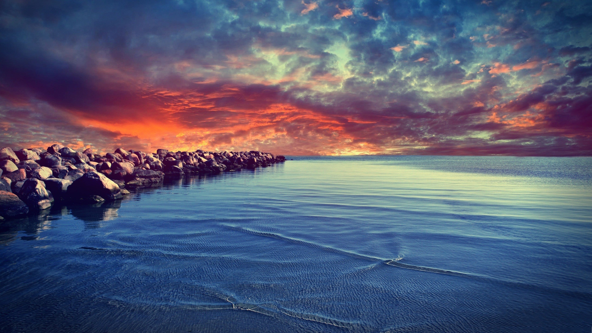 Красный закат над каменистым берегом