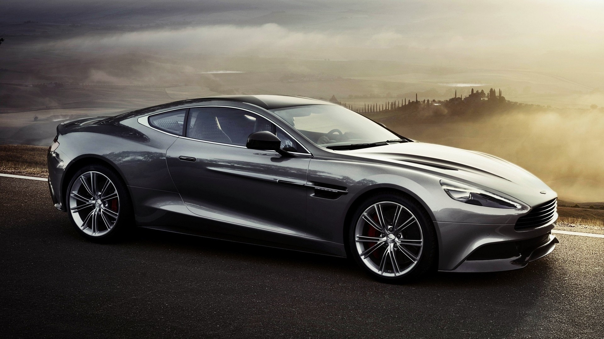 Dark gray Aston Martin on the background of the misty valley