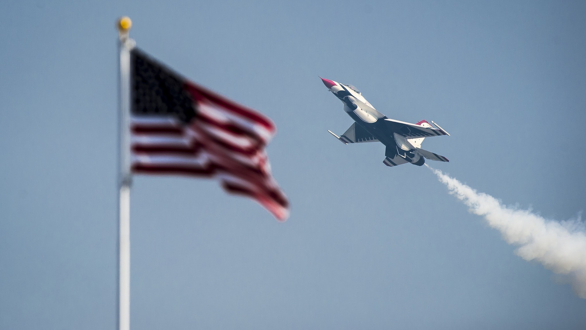 Истребитель F-16 Fighting Falcon пролетает над флагом США