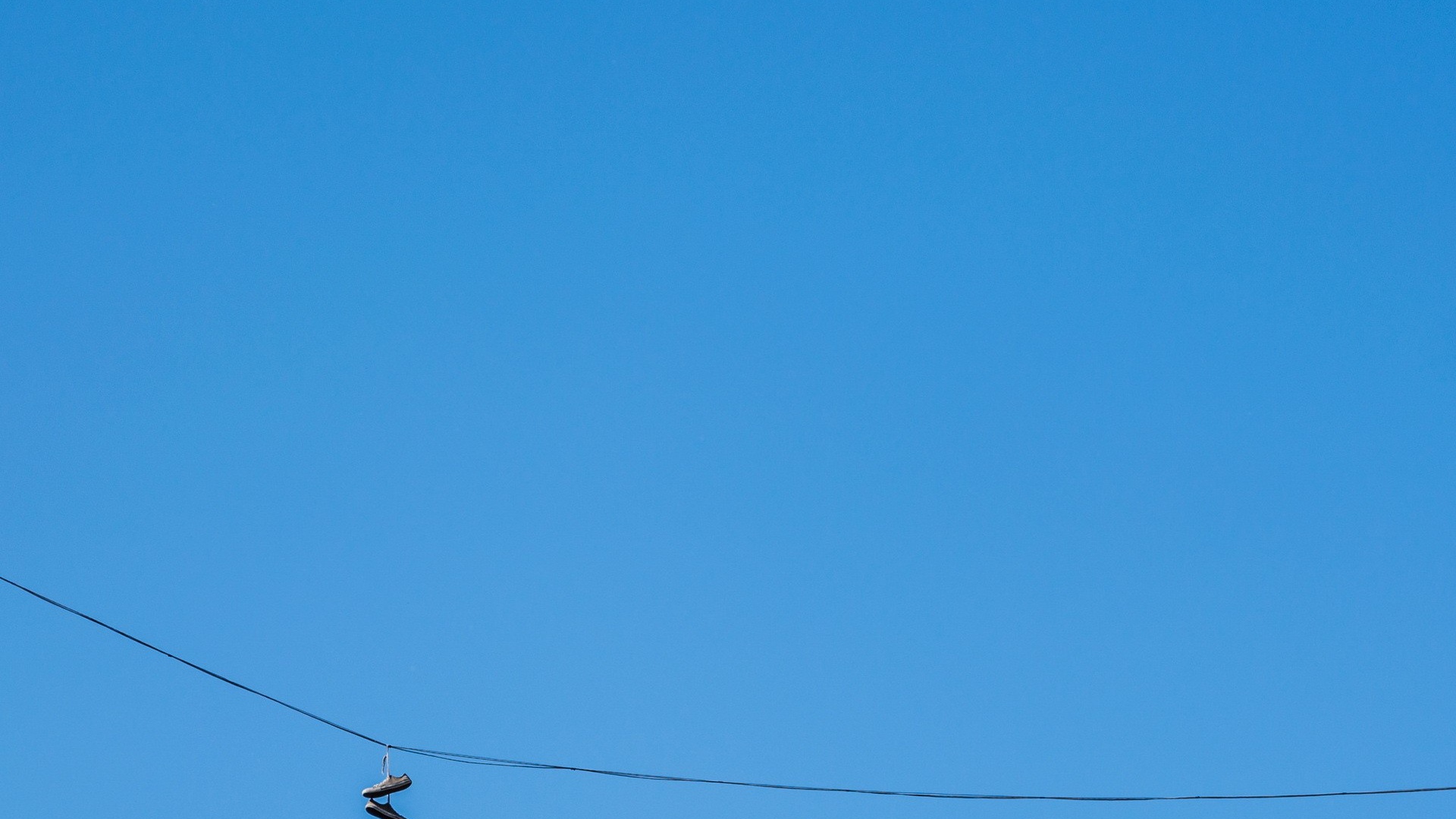 Кеды висят на проводе на фоне голубого неба