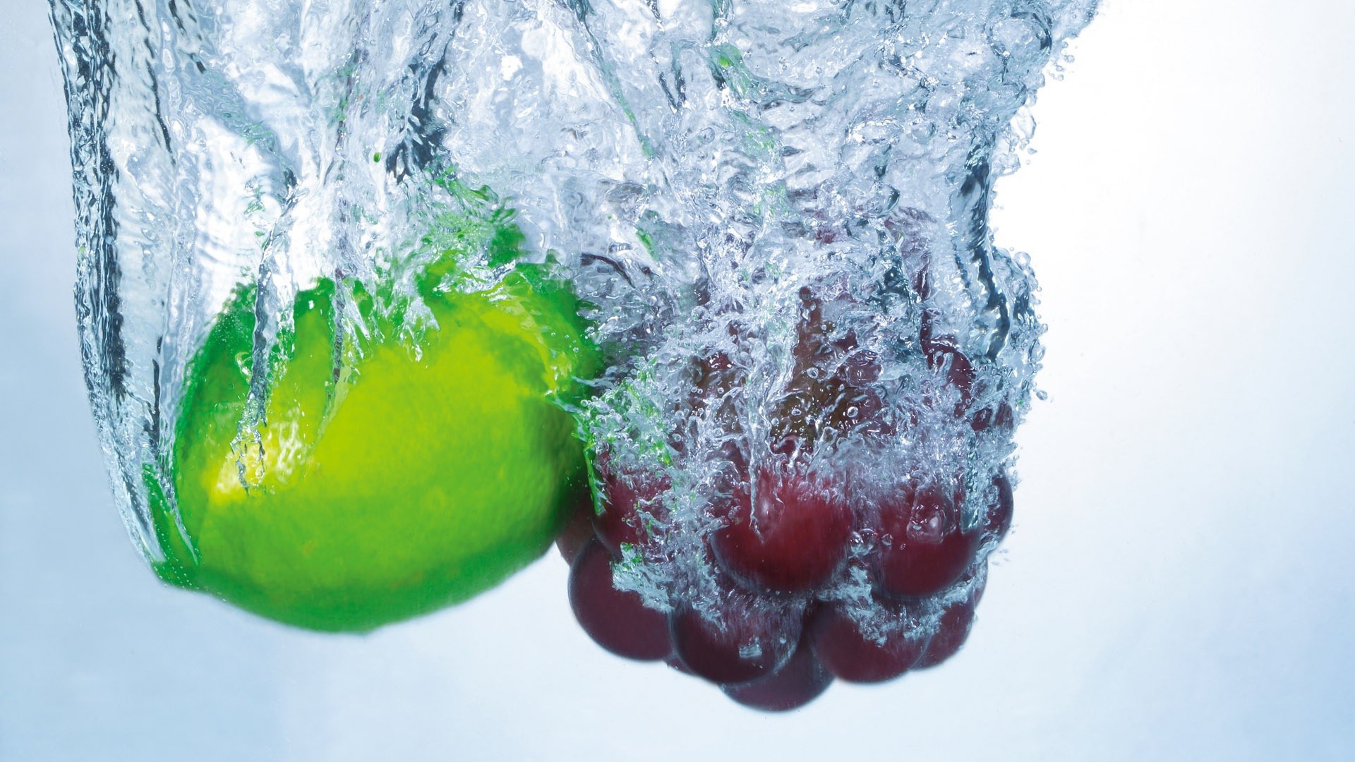 Зеленый лимон и кисть винограда в воде