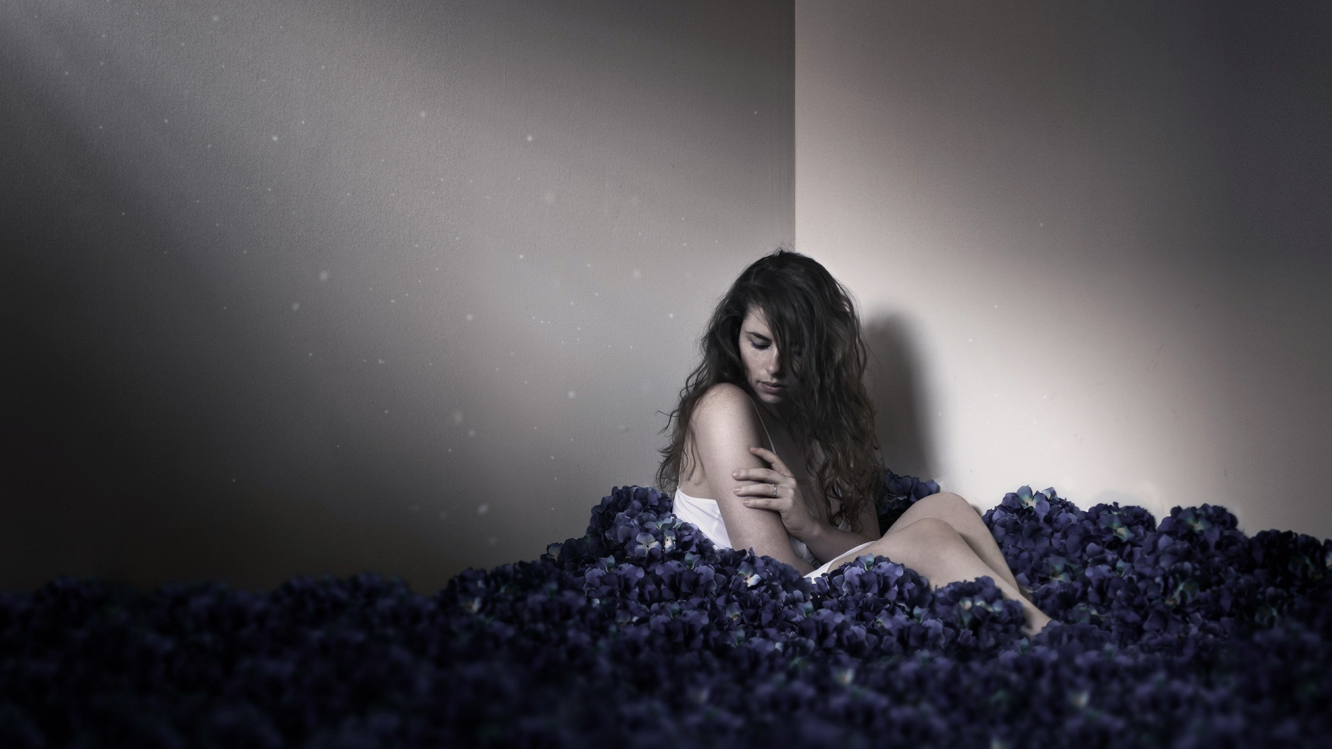 Девушка сидит в углу среди цветов