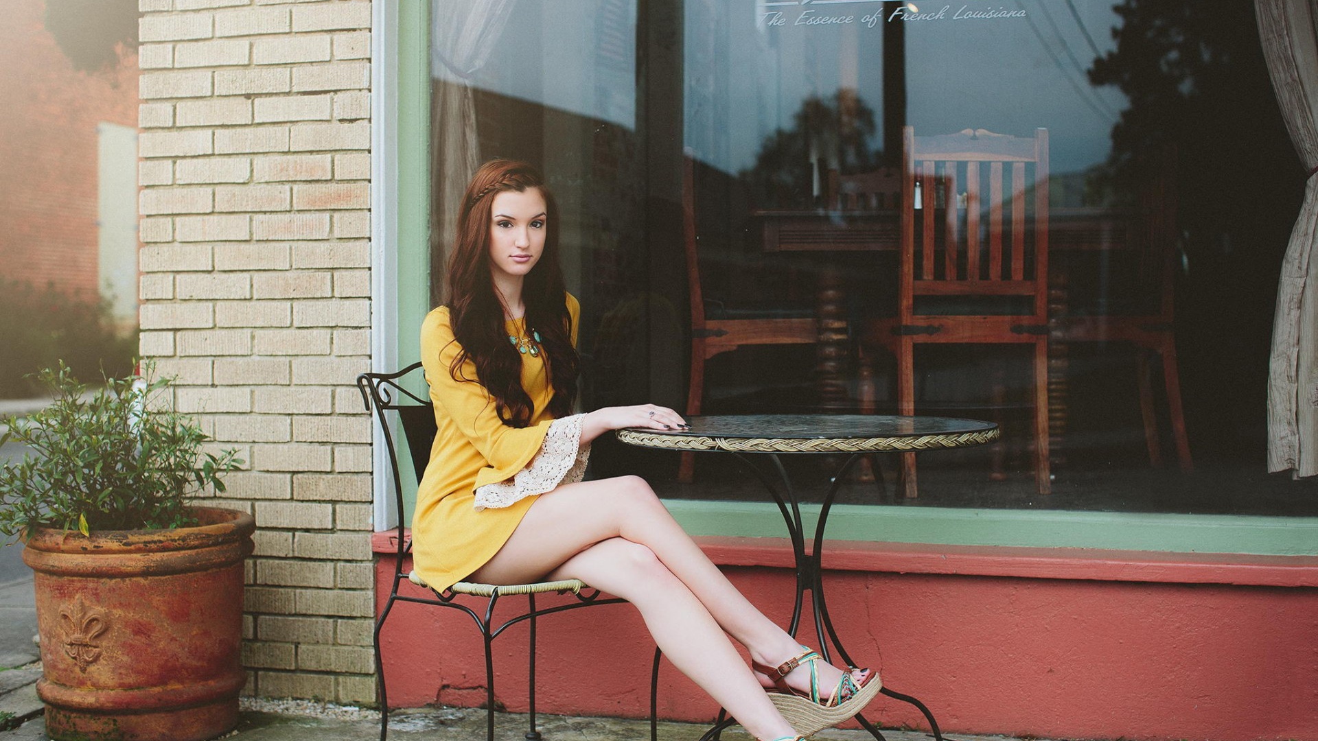 Девушка сидит за столиком уличного кафе