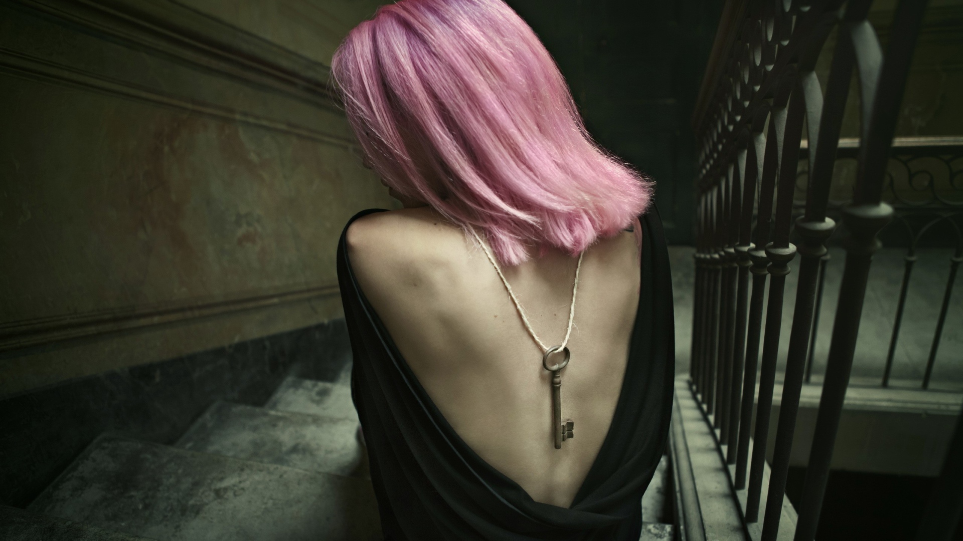 Девушка с розовыми волосами сидит на лестнице