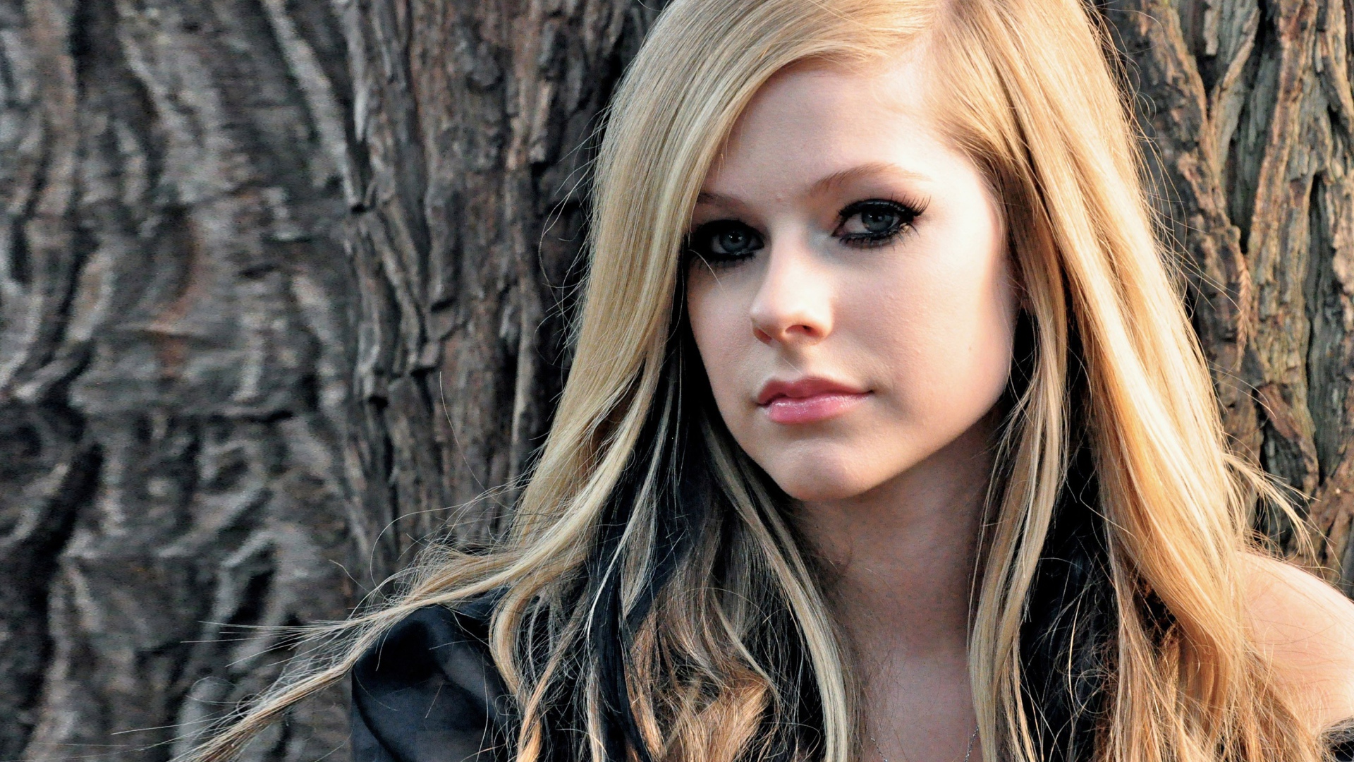 Блондинка Аврил Лавин на фоне коры дерева
