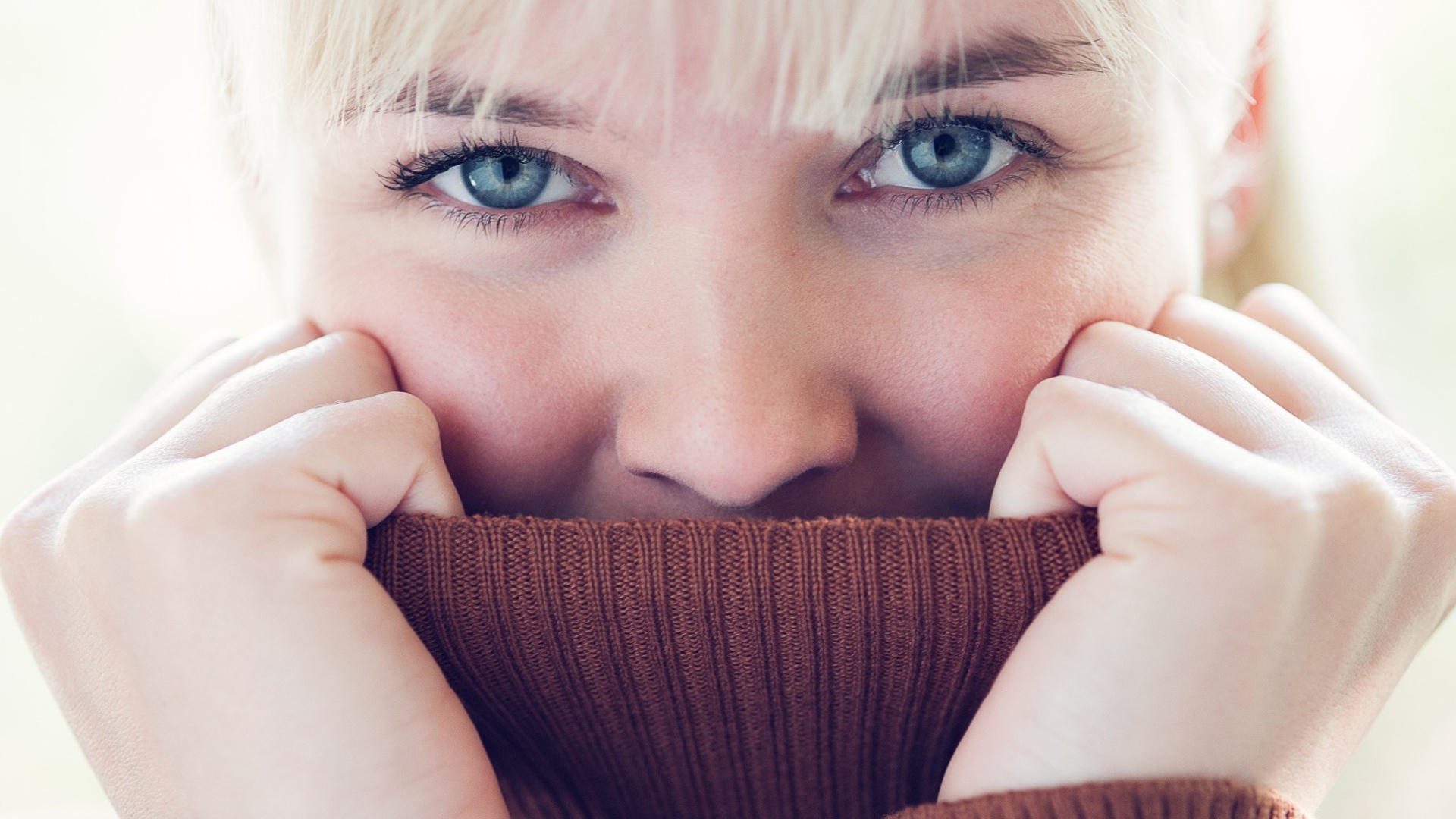 Блондинка прячет лицо в вороте свитера