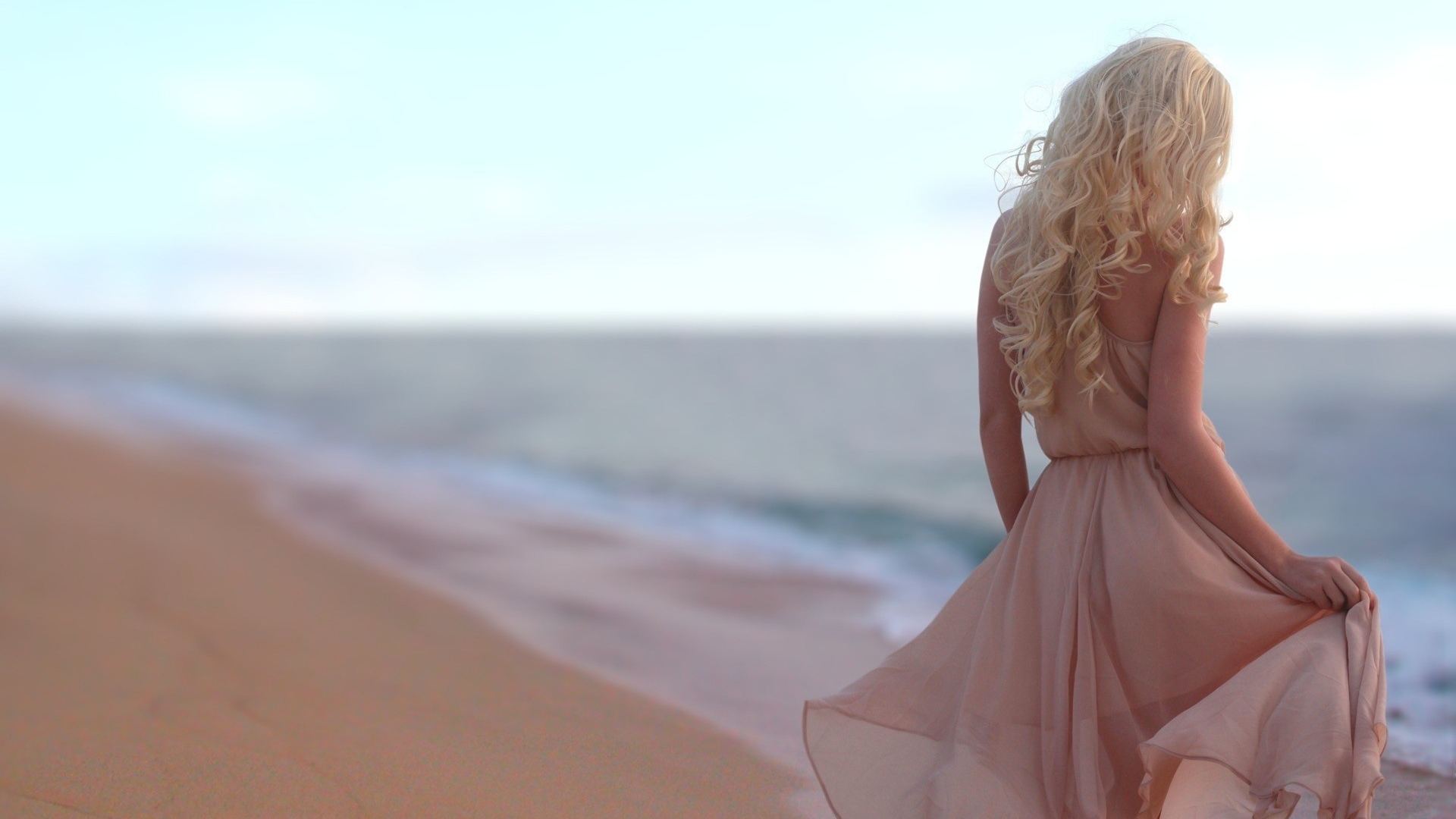 Блондинка в легком платье на пляже