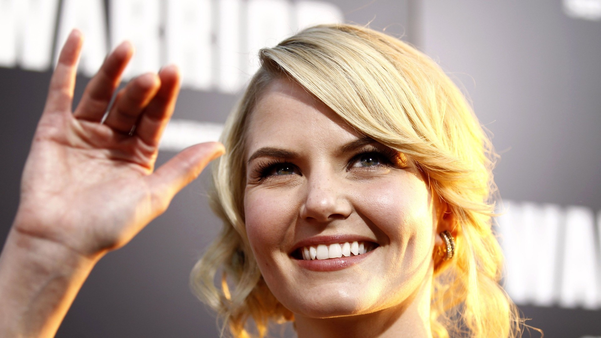 Блондинка улыбается и машет