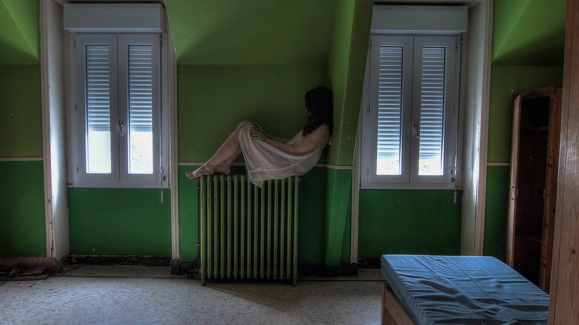 Девушка в ночной рубашке сидит на батарее