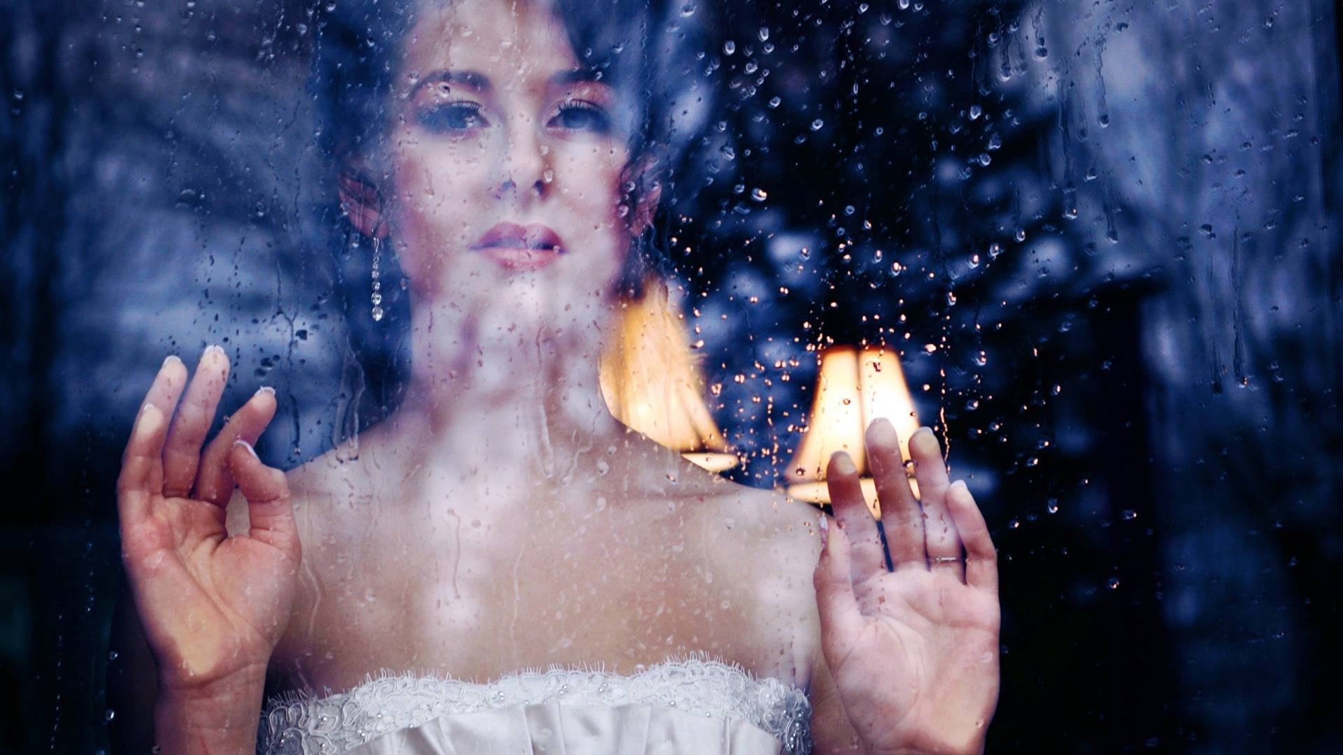 Девушка в белом платье за мокрым стеклом