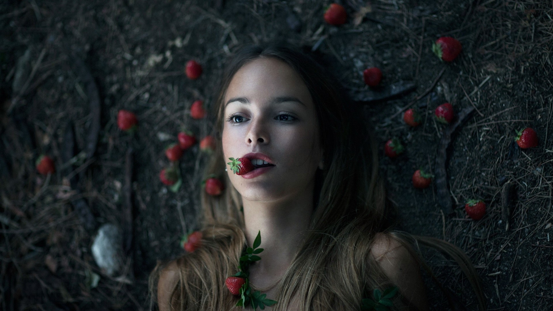 Девушка лежит на земле среди клубники