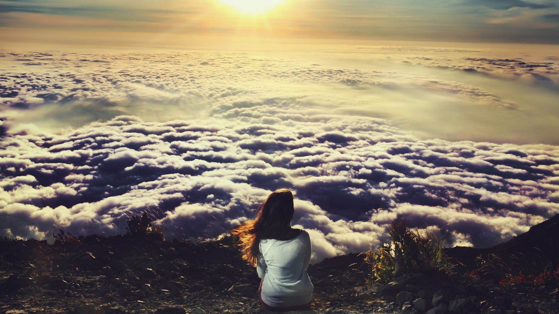 Девушка сидит и смотрит на облака