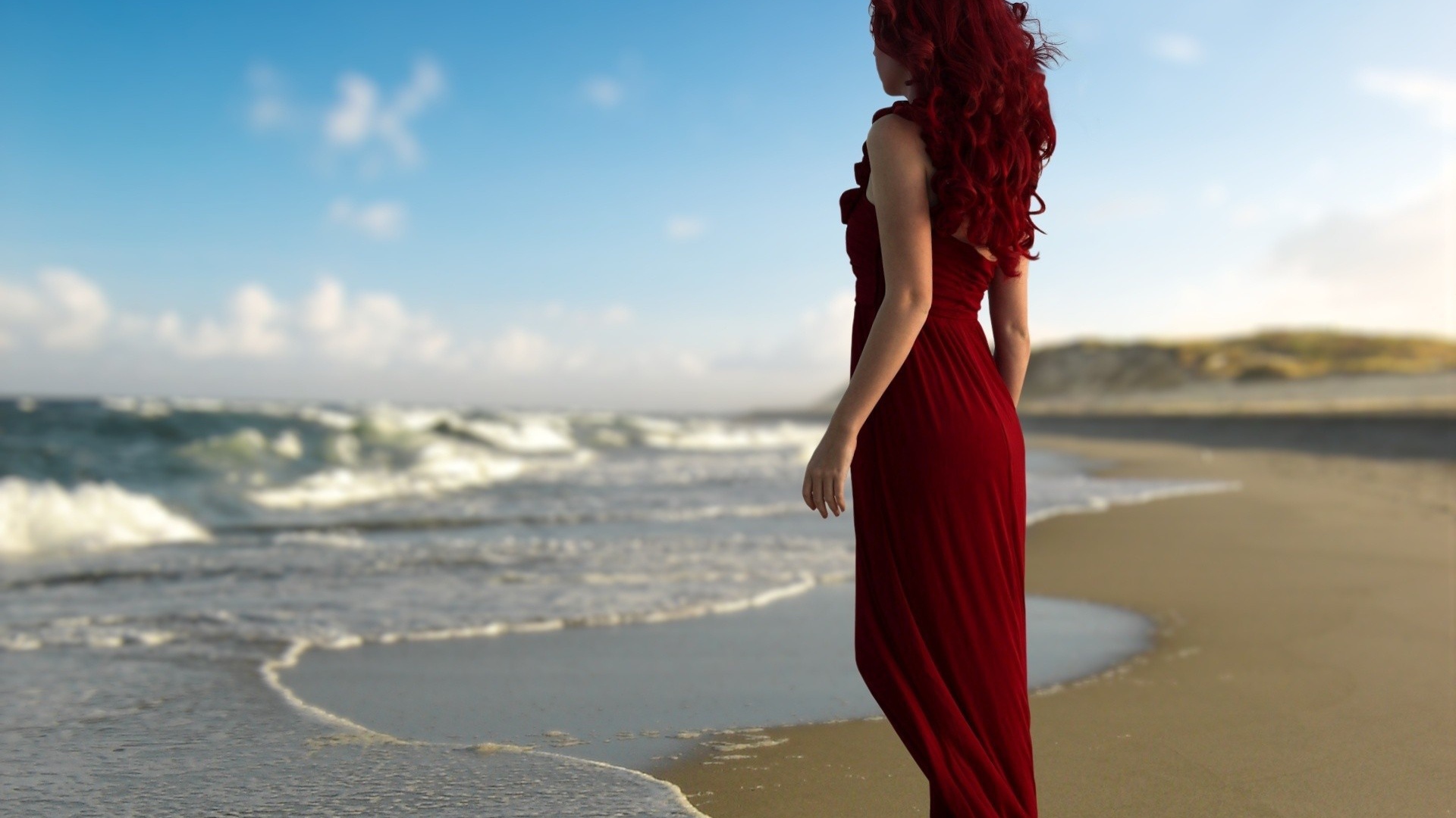 Девушка с красными волосами в красном платье на берегу моря
