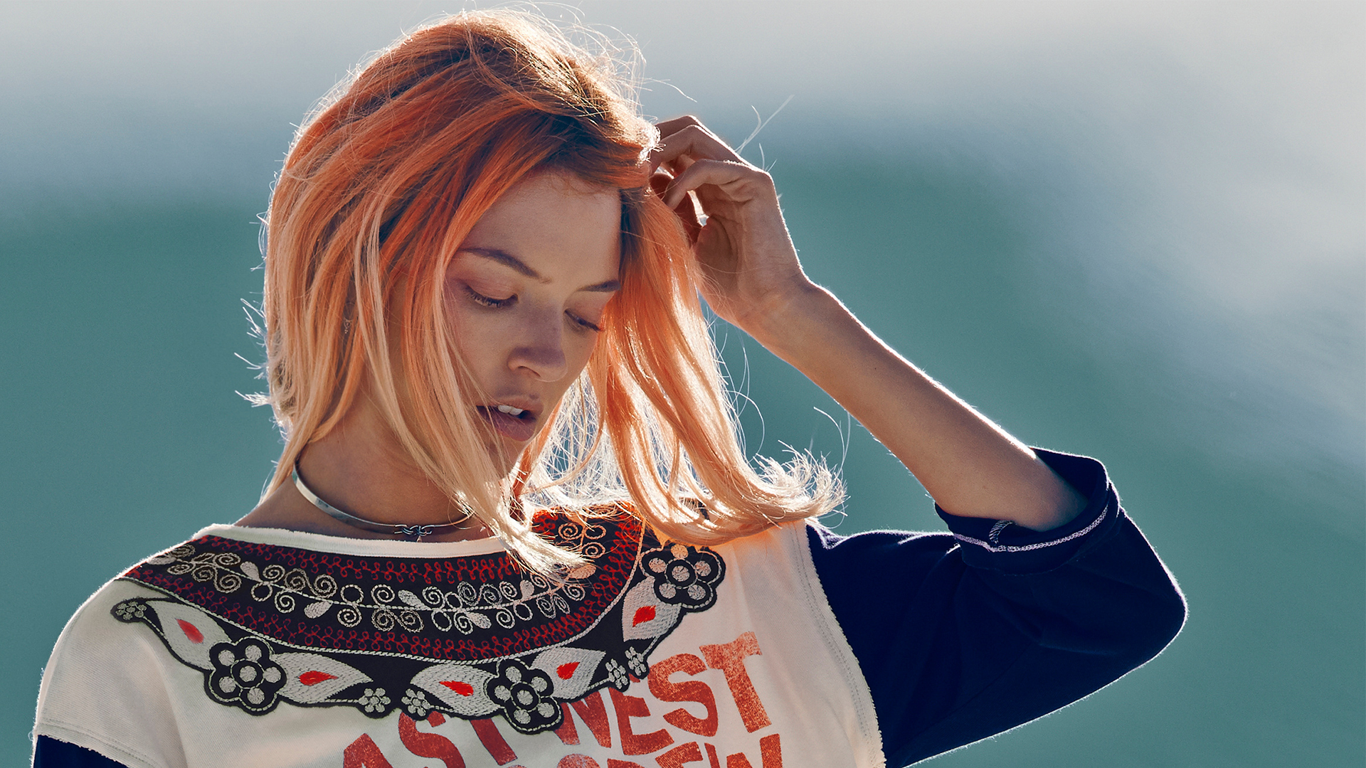 Рыжая девушка на ветру поправляет волосы