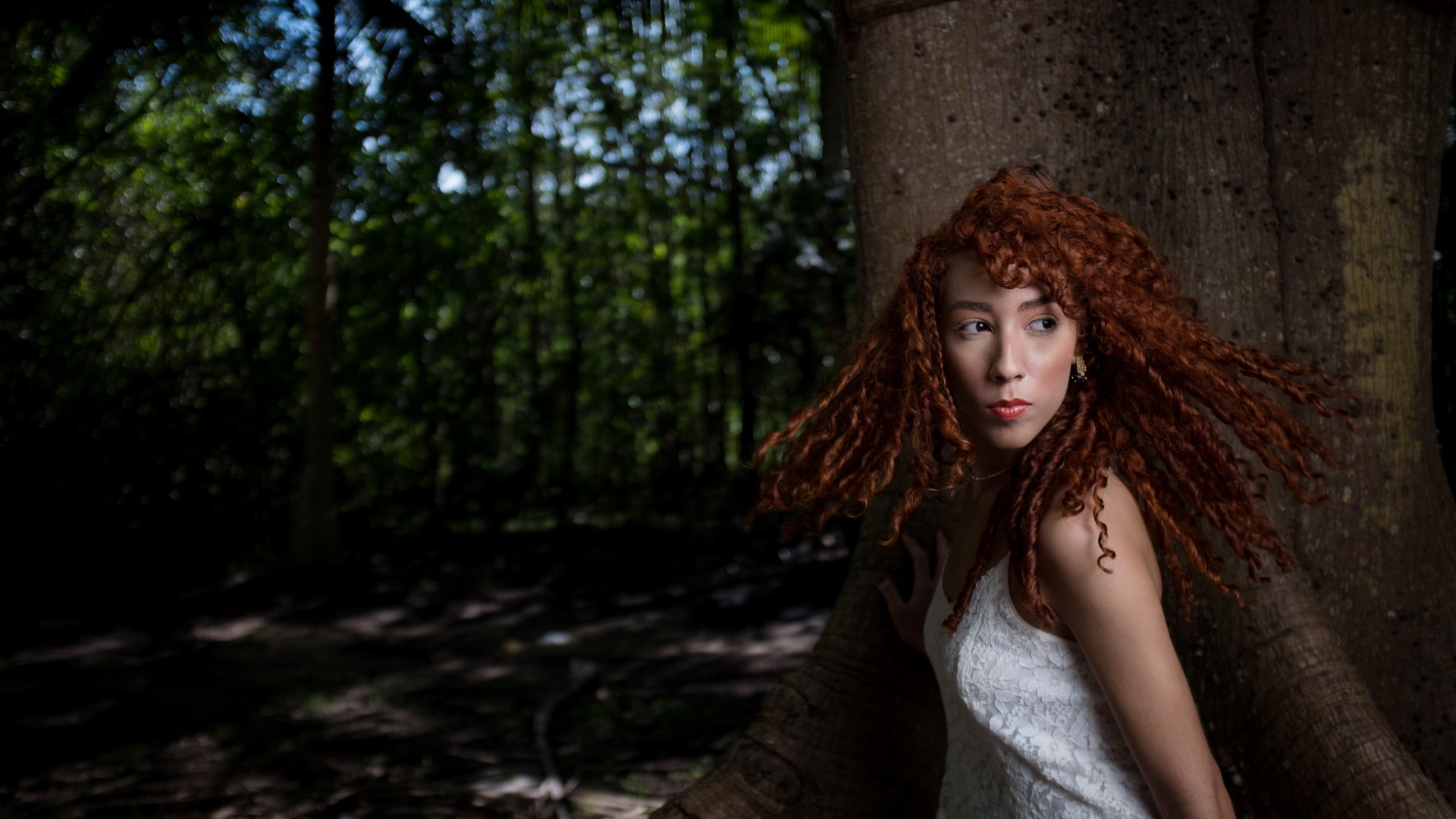 Рыжая девушка с кудрями у большого дерева