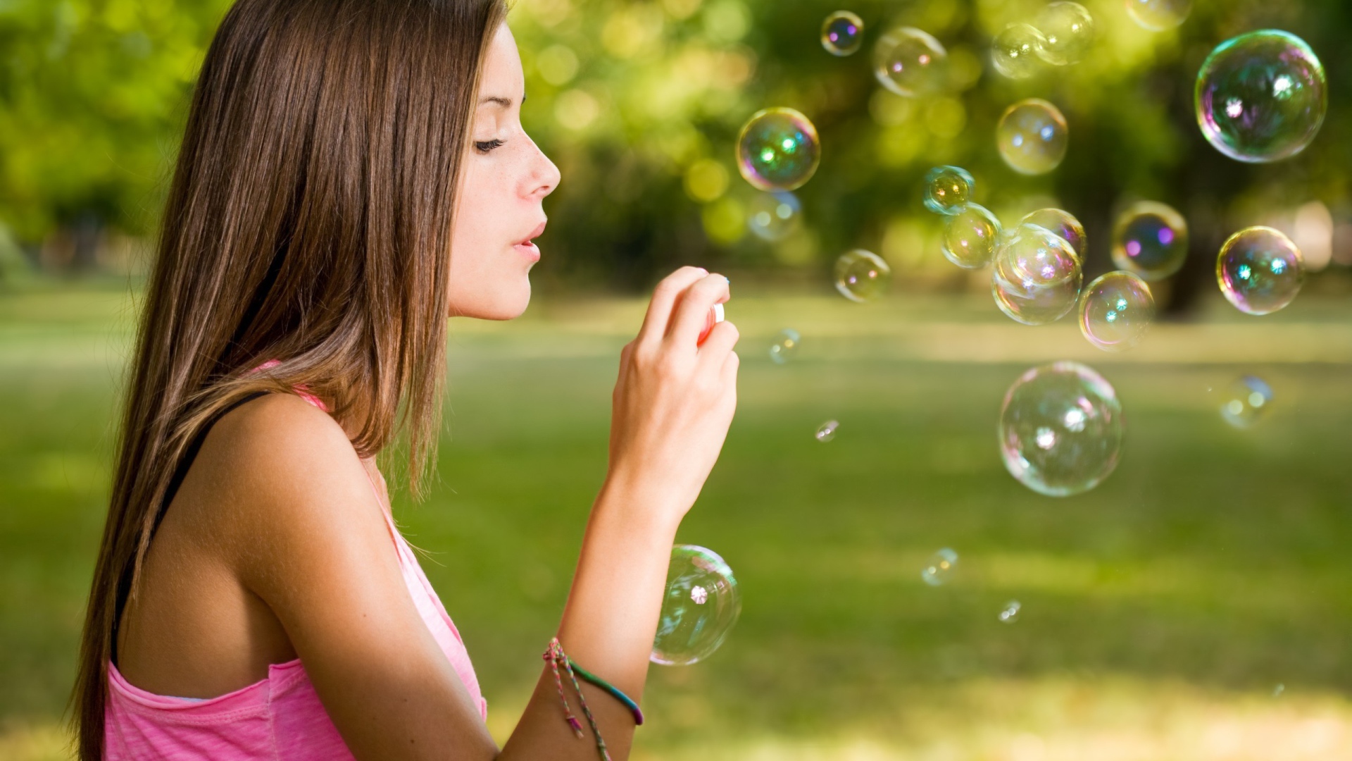 Девушка в розовой футболке запускает мыльные пузыри