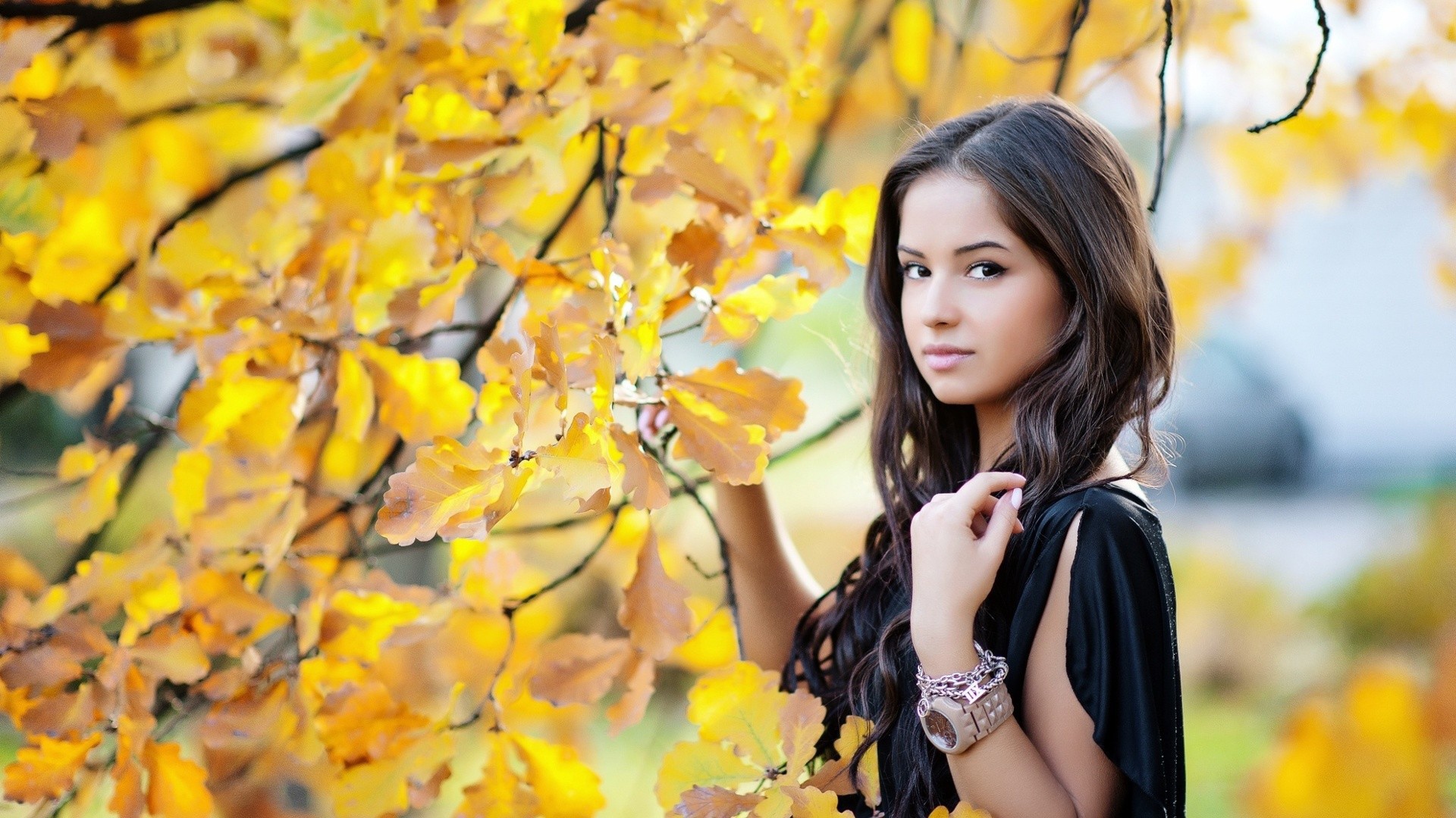 Молодая брюнетка у осеннего дерева