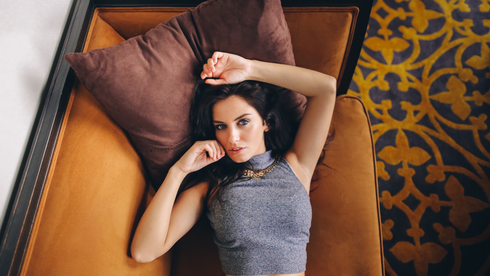 Модель Aurela Skandaj лежит на диване