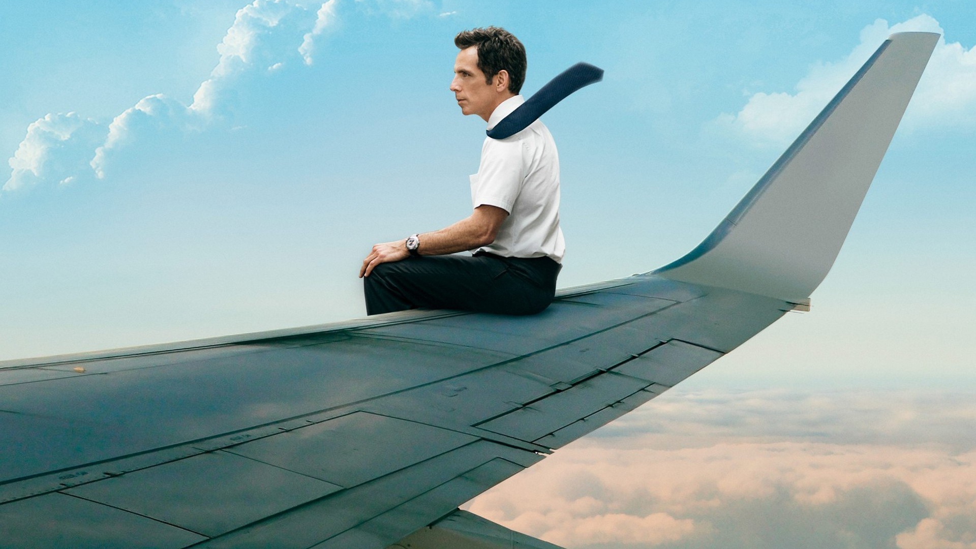 The man is sitting on the wing of an airplane