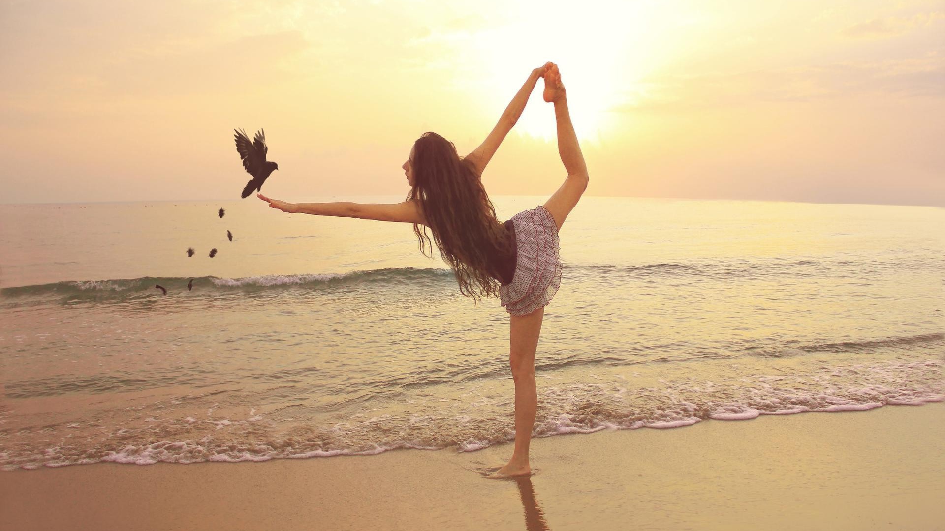 Балерина на берегу моря с птицей