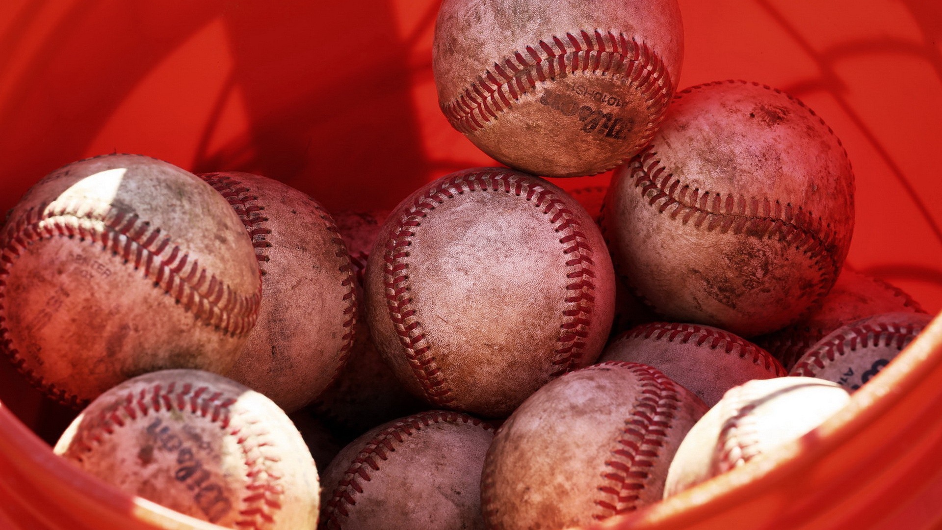 Красное ведро с мячами для бейсбола