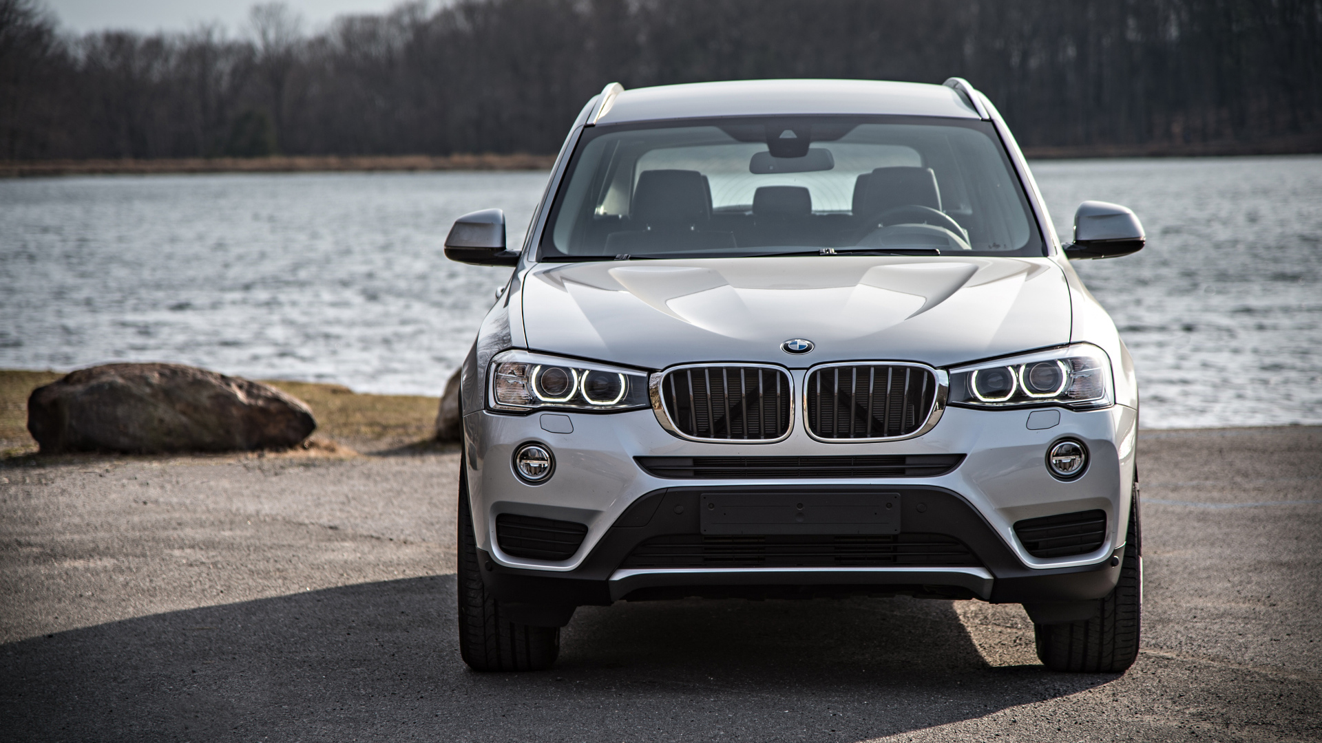 Серебристый автомобиль BMW X3 у водоема 