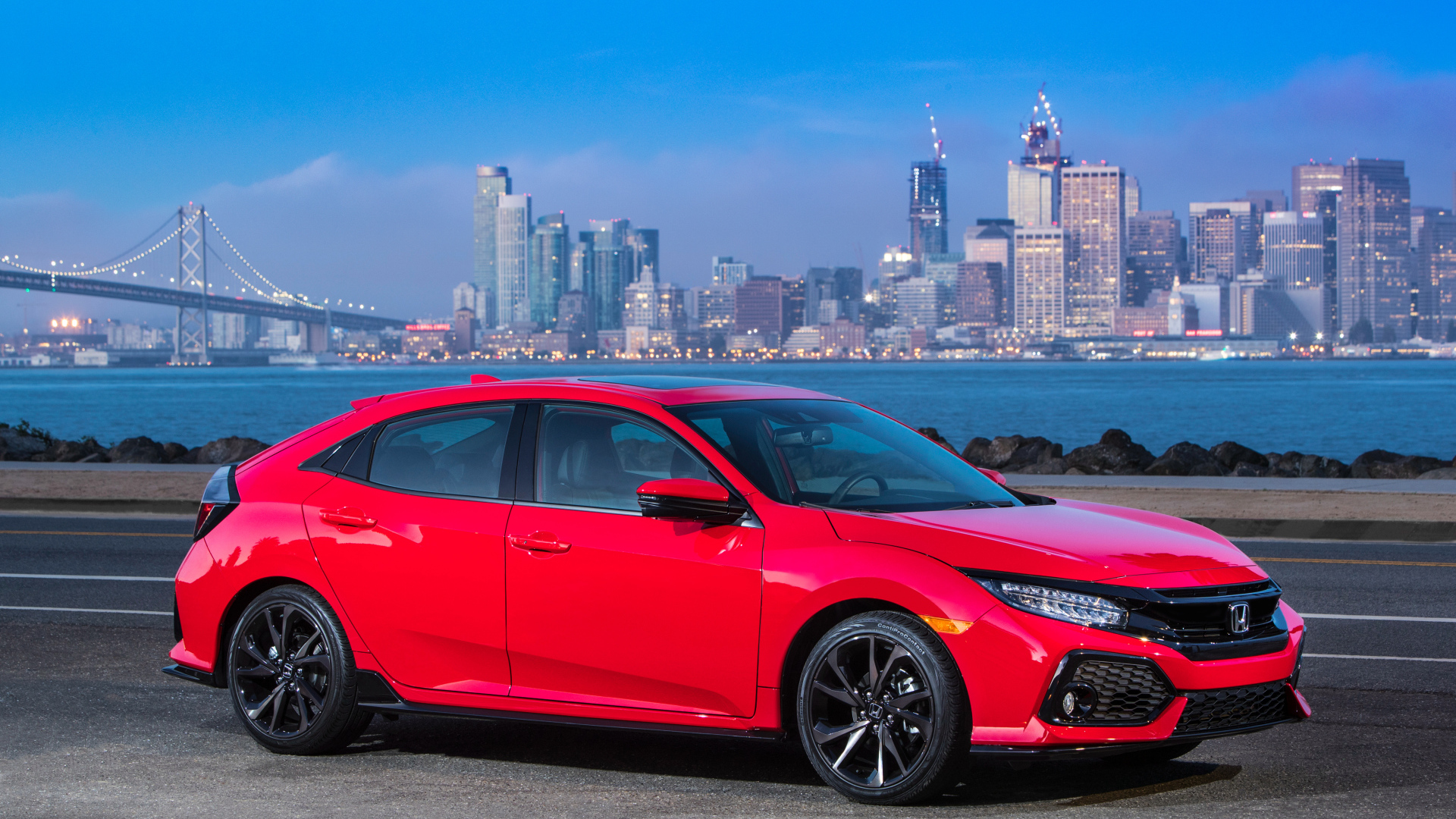 Красный автомобиль Honda Civic Touring Hatchback, 2017 на фоне города 