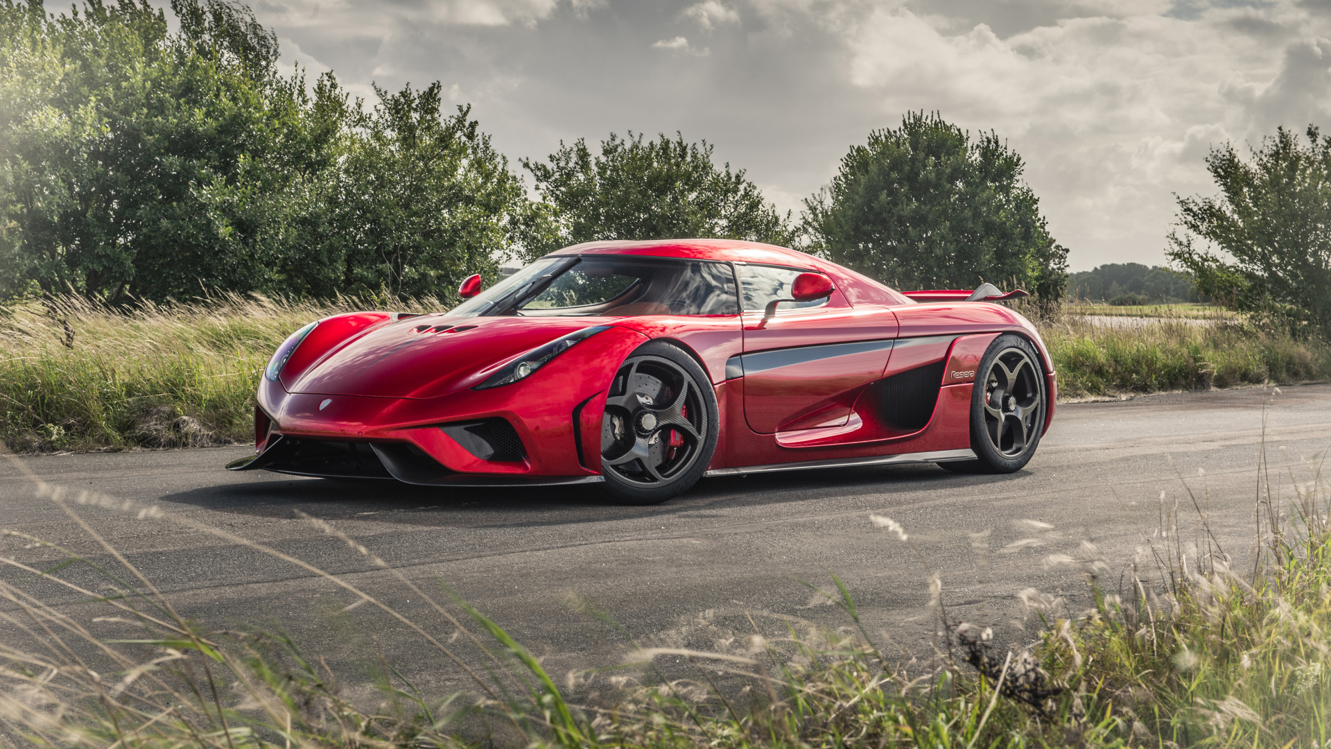 Красный спортивный автомобиль Koenigsegg Regera на дороге