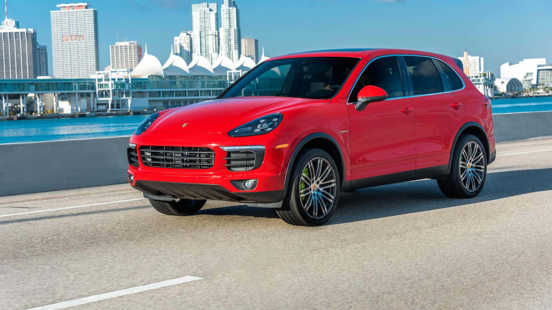 Красный автомобиль Porsche Cayenne на фоне города 