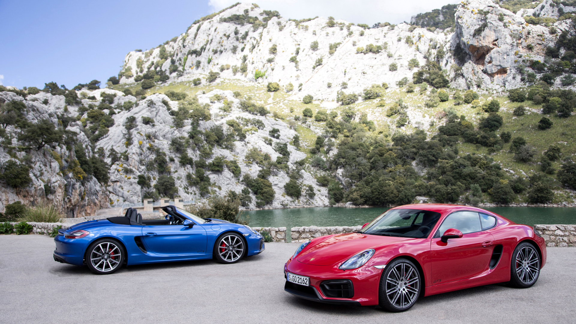 Два спортивных автомобиля Porsche Boxster и Porsche Cayman GTS  у воды 