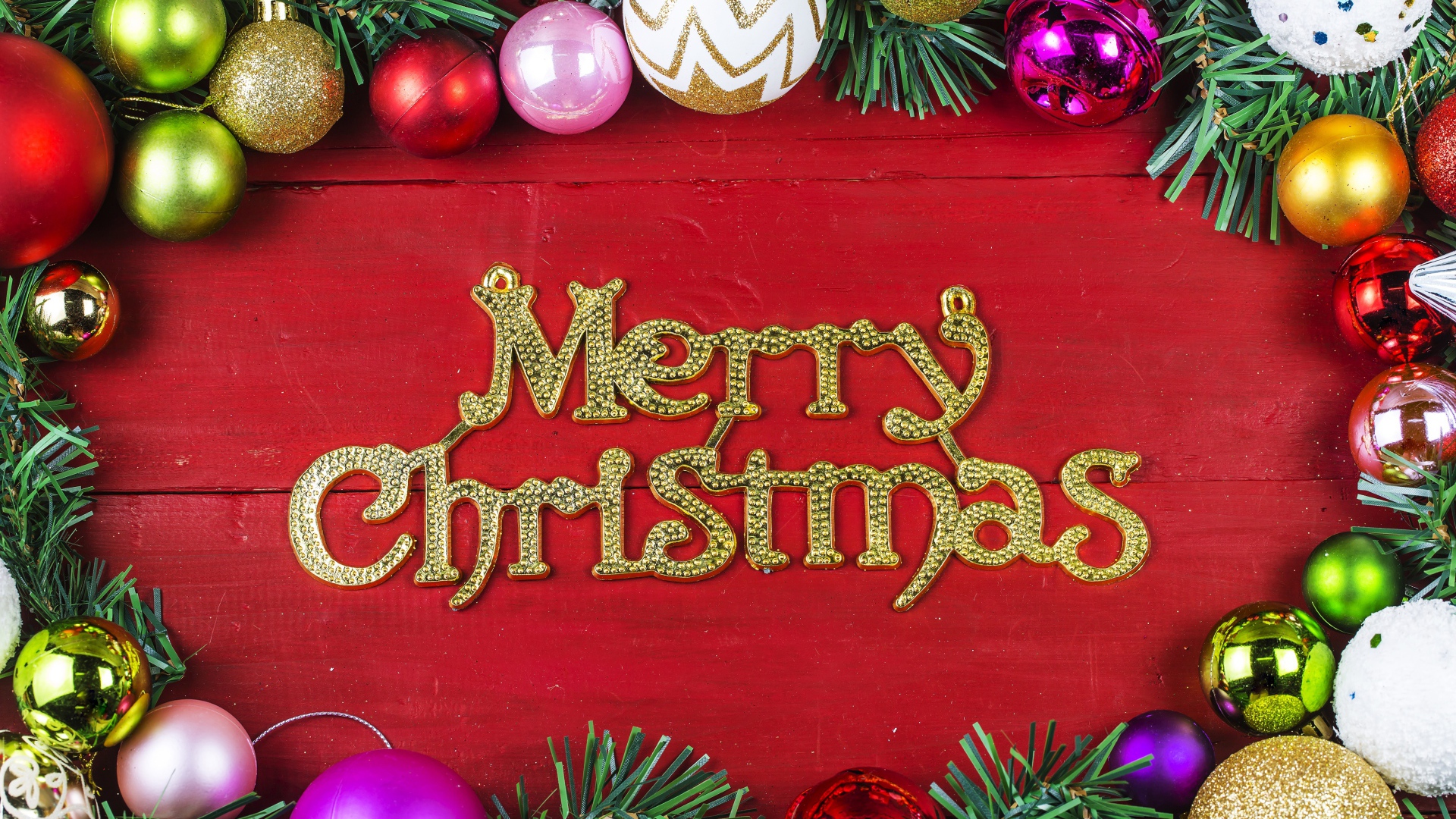 Надпись Merry Christmas на красном фоне с елочными игрушками на Рождество