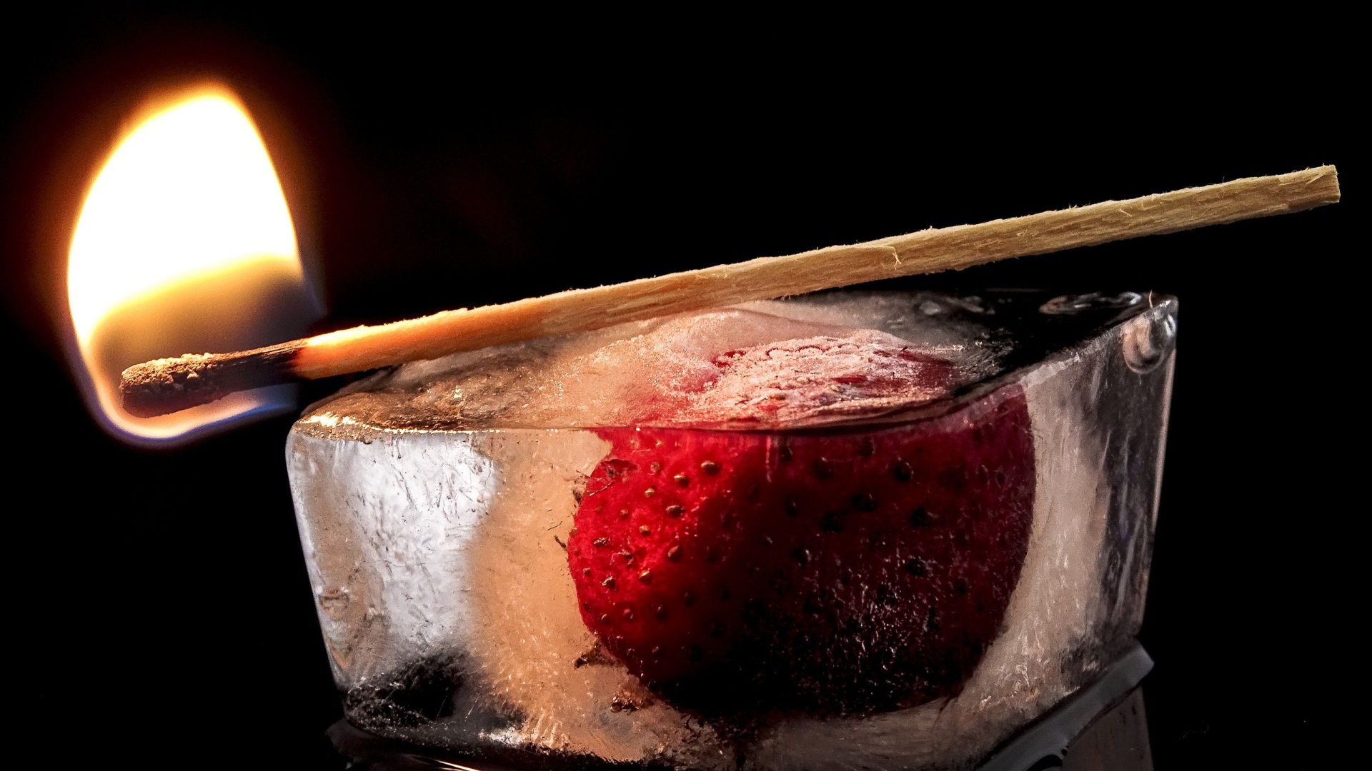 Зажженная спичка на кусочке льда с клубникой 