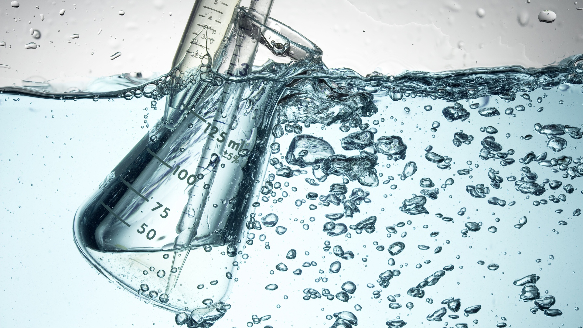 Измерительная чашка в воде с пузырями 