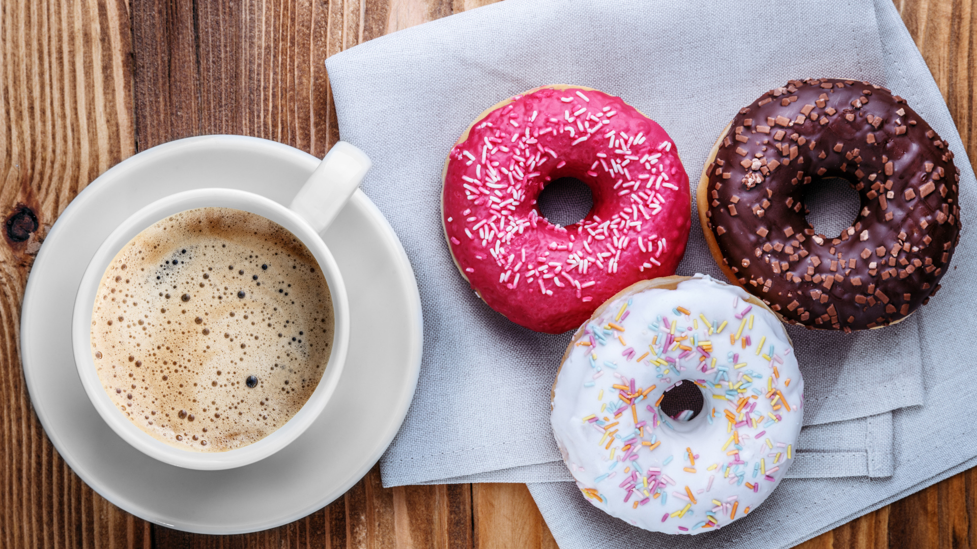 Чашка кофе с тремя аппетитными пончиками на столе