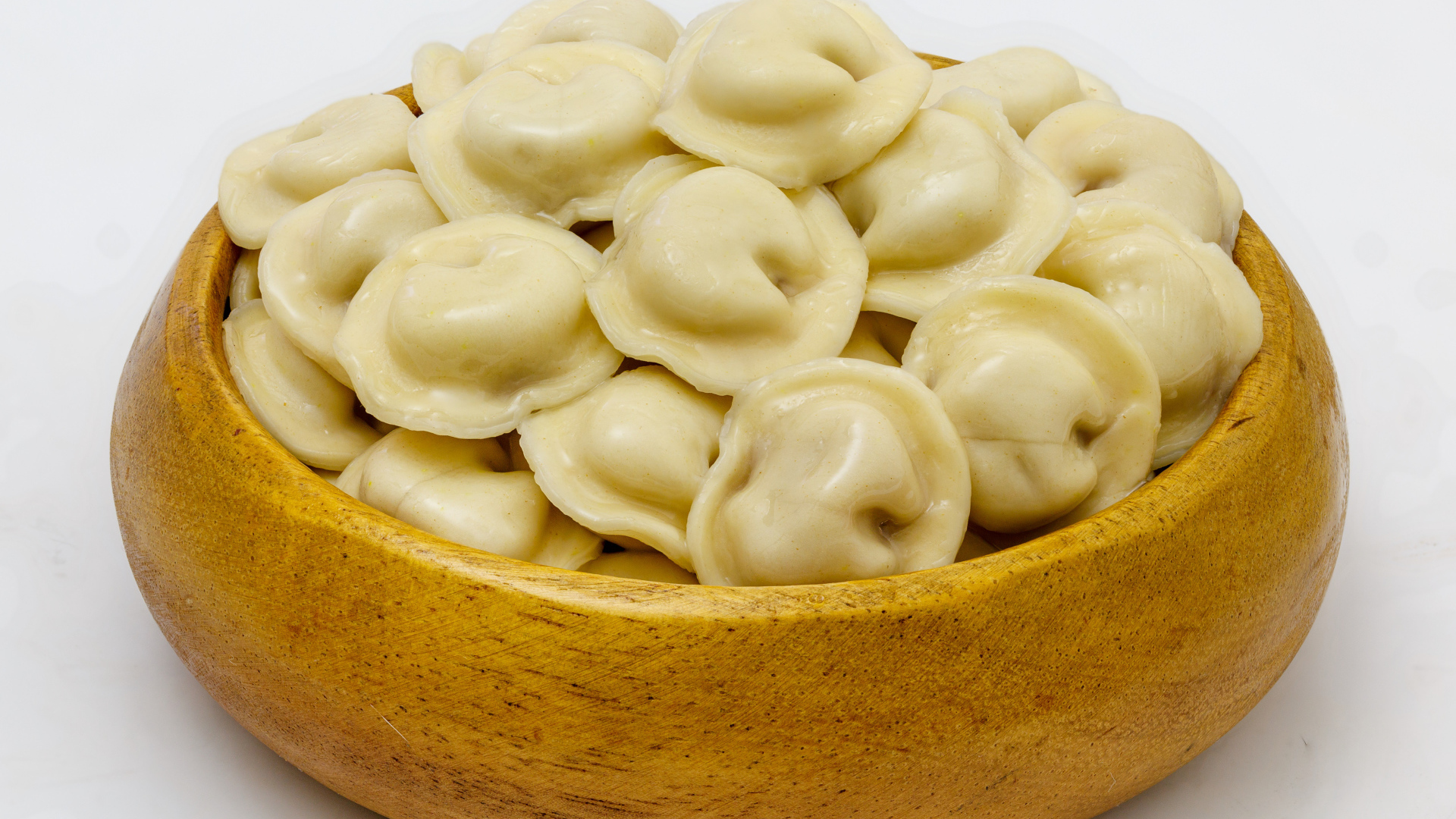 Аппетитные пельмени в деревянной миске на сером фоне