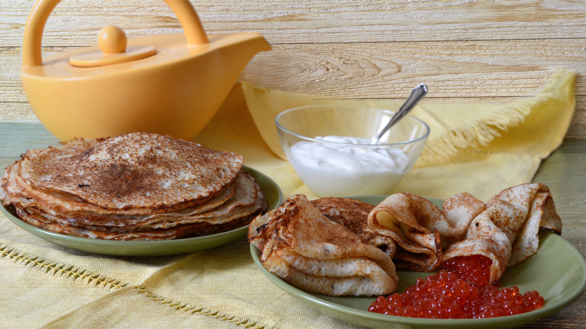 Аппетитные блинчики со сметаной и красной икрой на столе