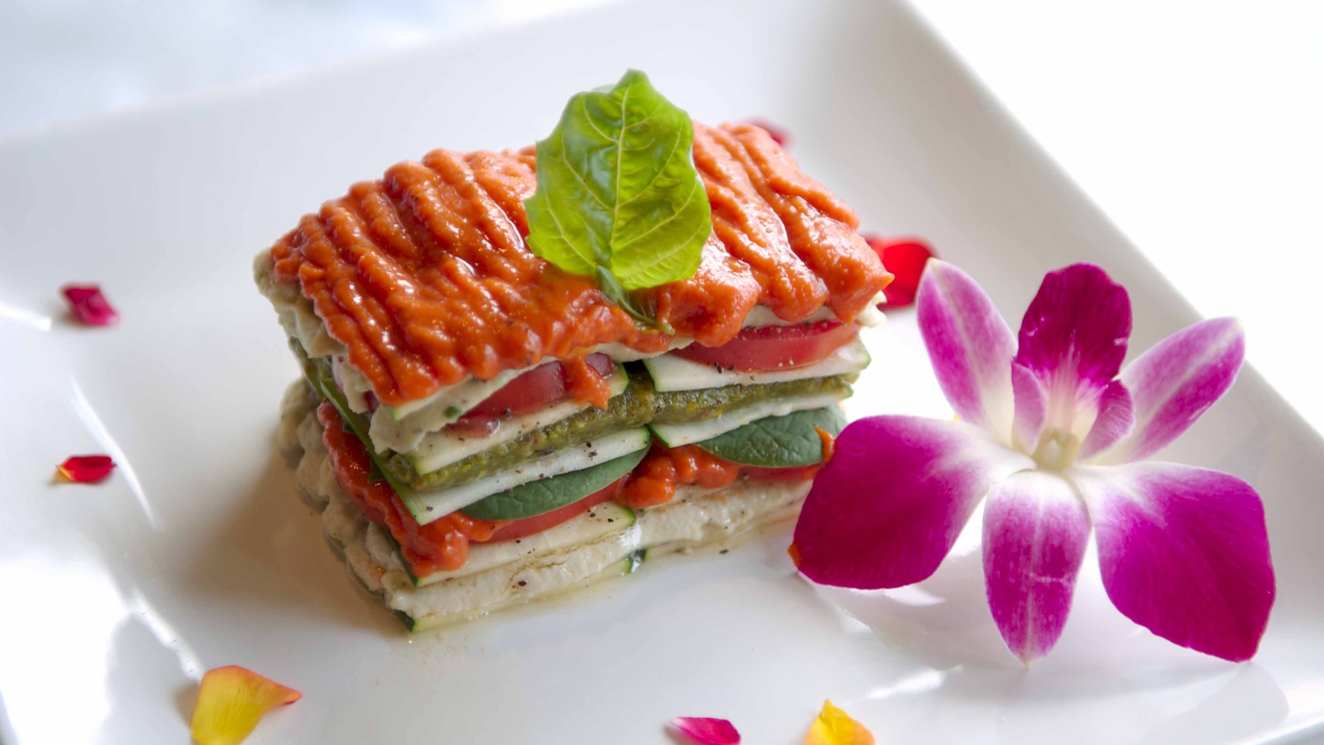 Аппетитный овощной бутерброд на белой тарелке с цветком