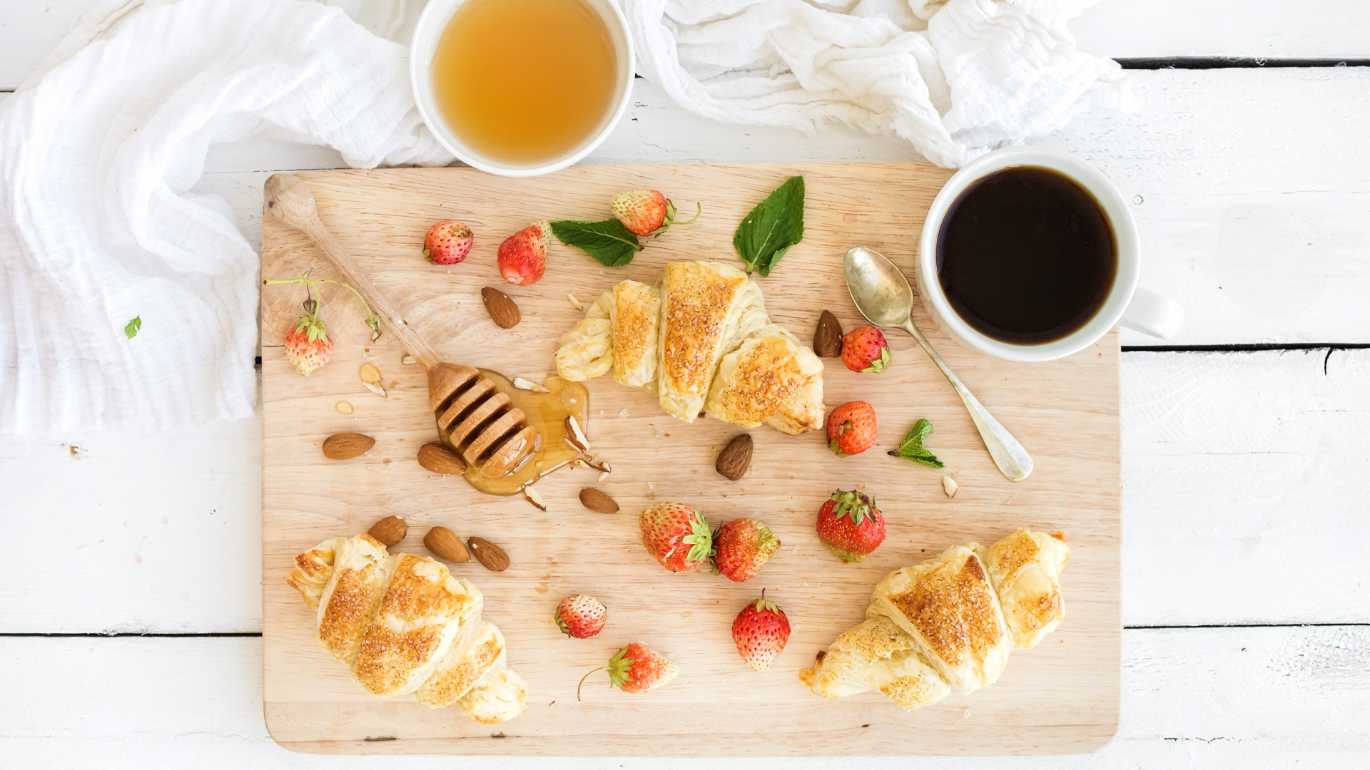 Круассаны, мед, свежие ягоды клубники и кофе на завтрак