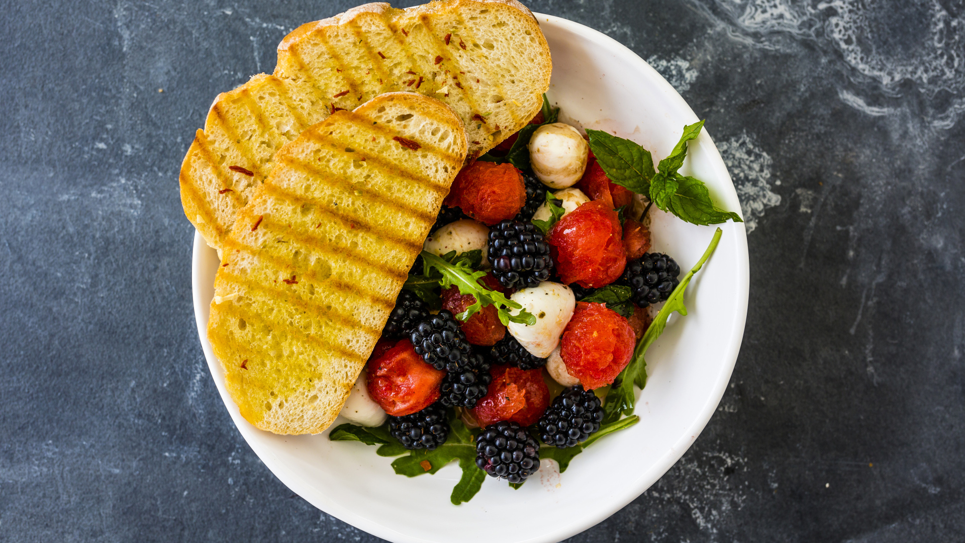 Гренки с салатом из ягод на белой тарелке