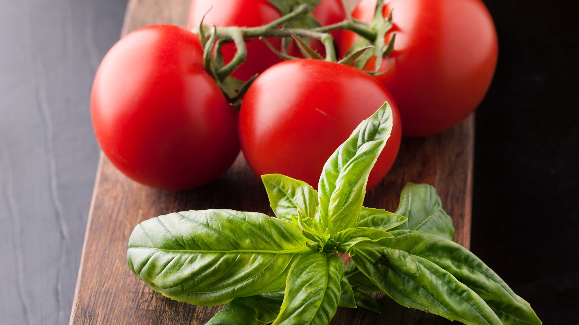 Свежие помидоры на разделочной с зеленью