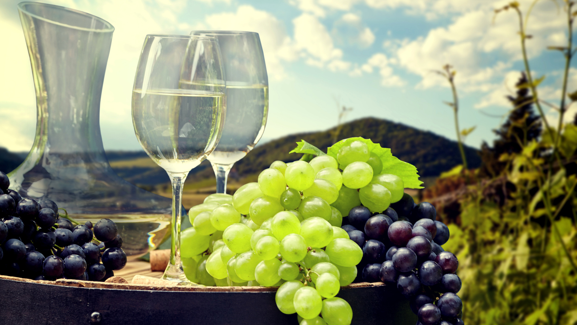 Гроздья синего и белого винограда с фужерами на деревянной бочке