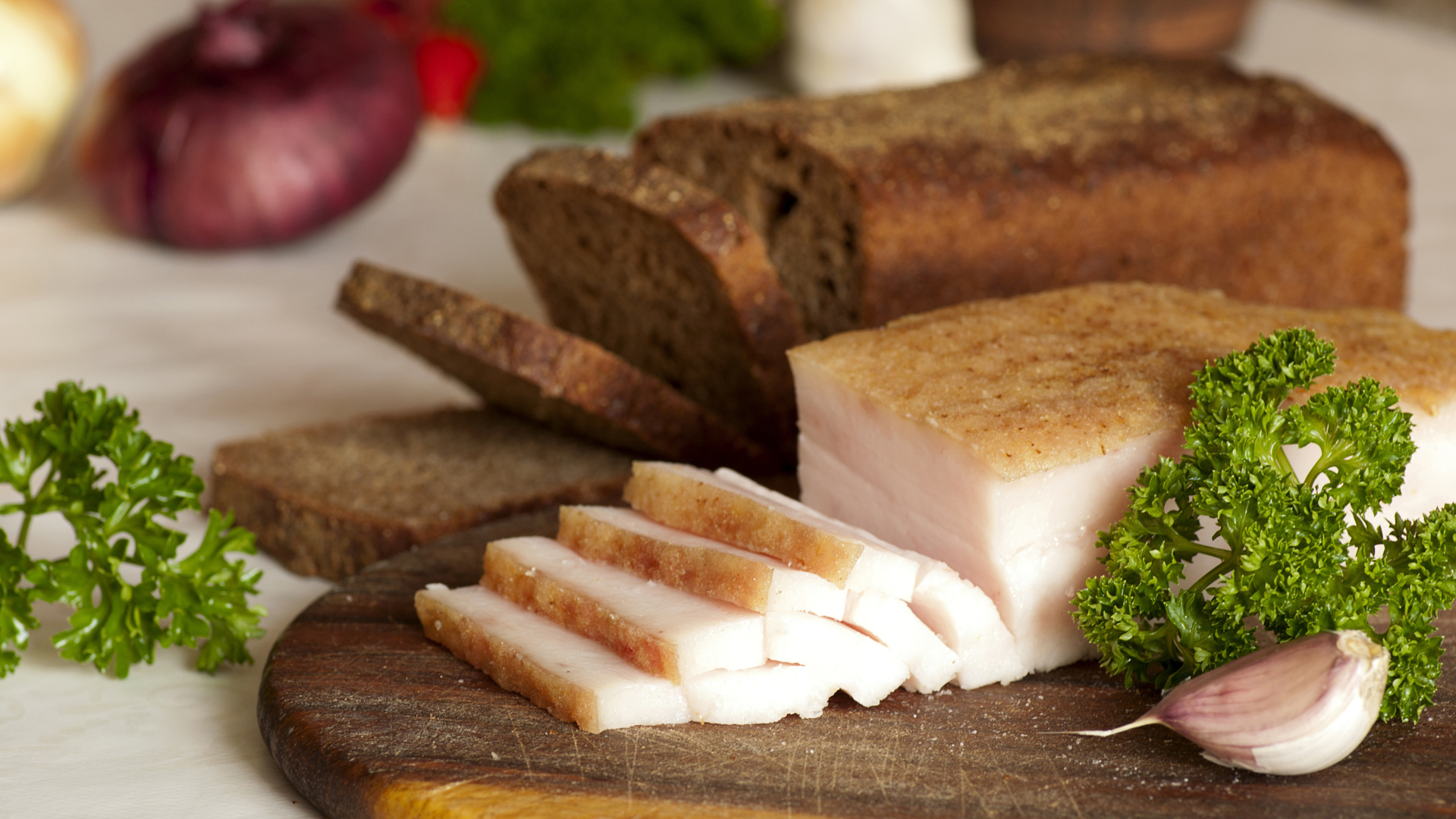 Нарезанное кусочками сало и черный хлеб на разделочной доске