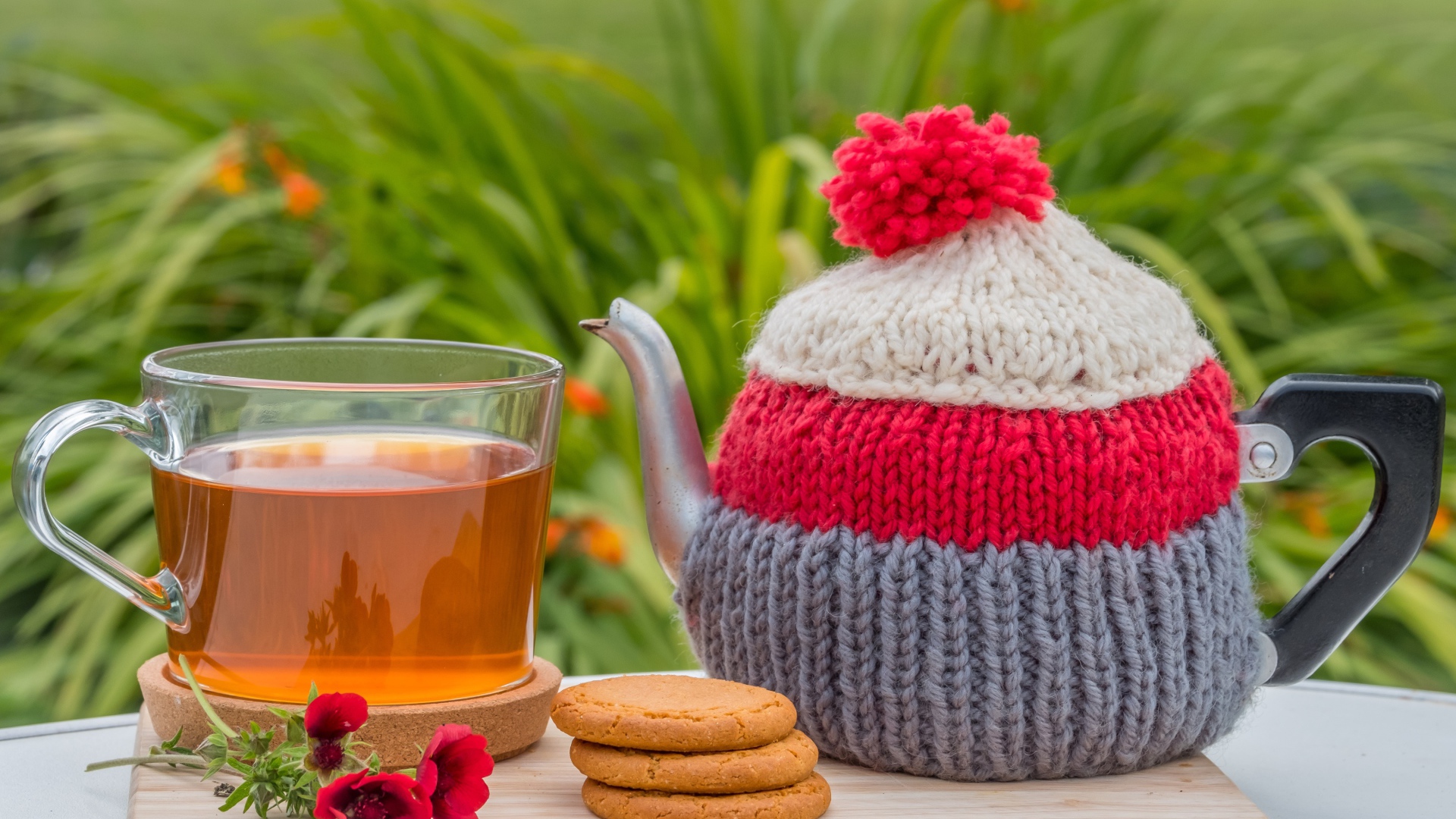 Чайник с чашкой чая на столе с печеньем и цветами