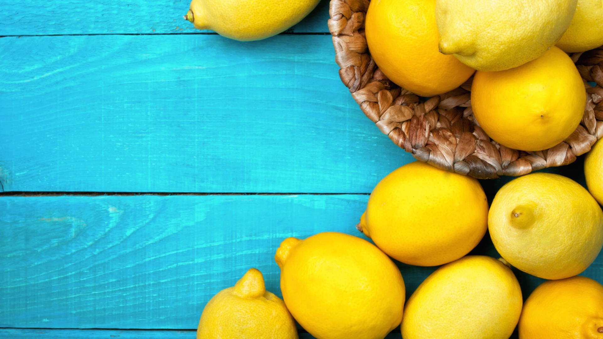 Свежие желтые лимоны лежат на голубой поверхности стола