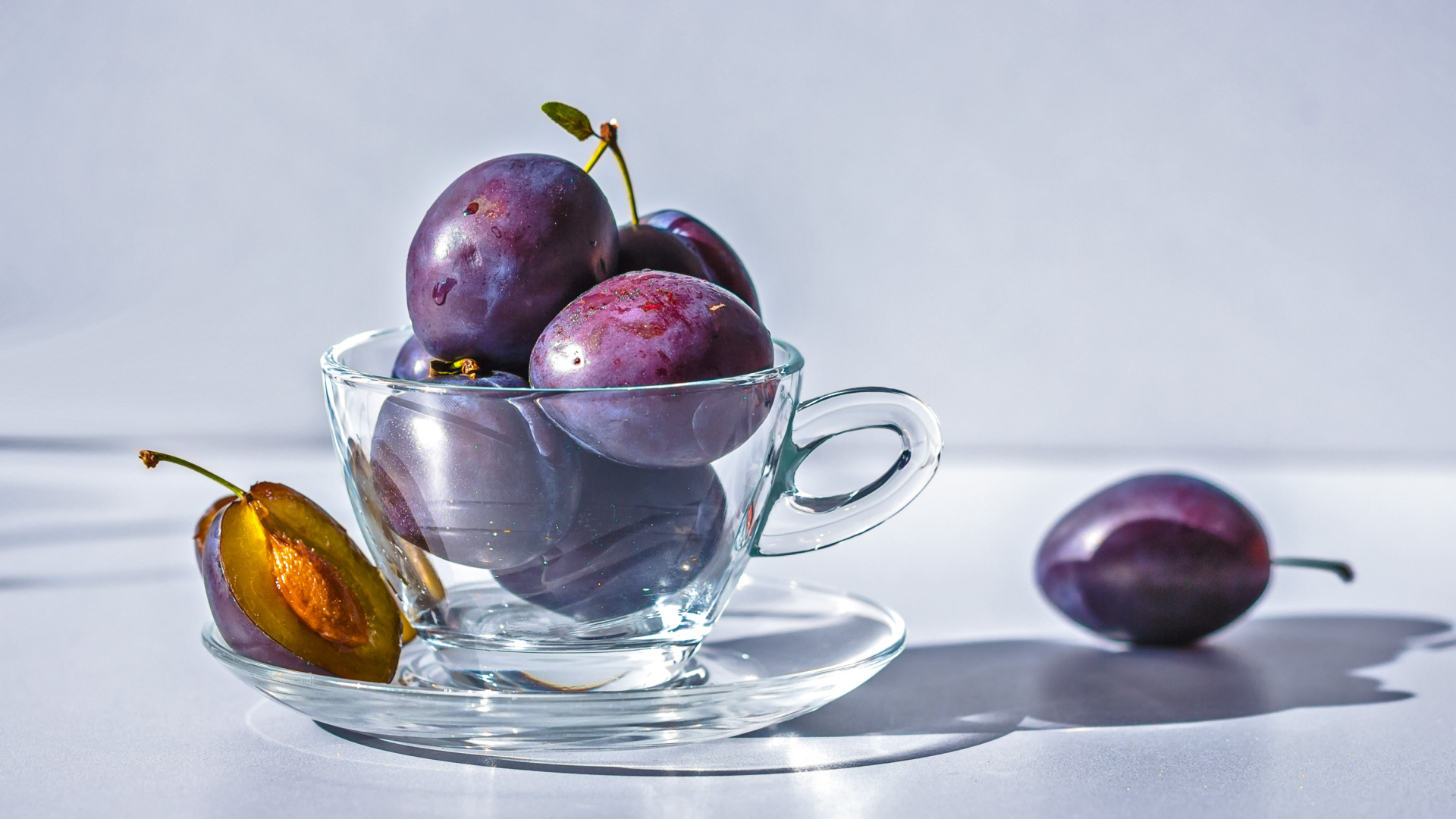Спелые синие сливы на столе в стеклянной чашке