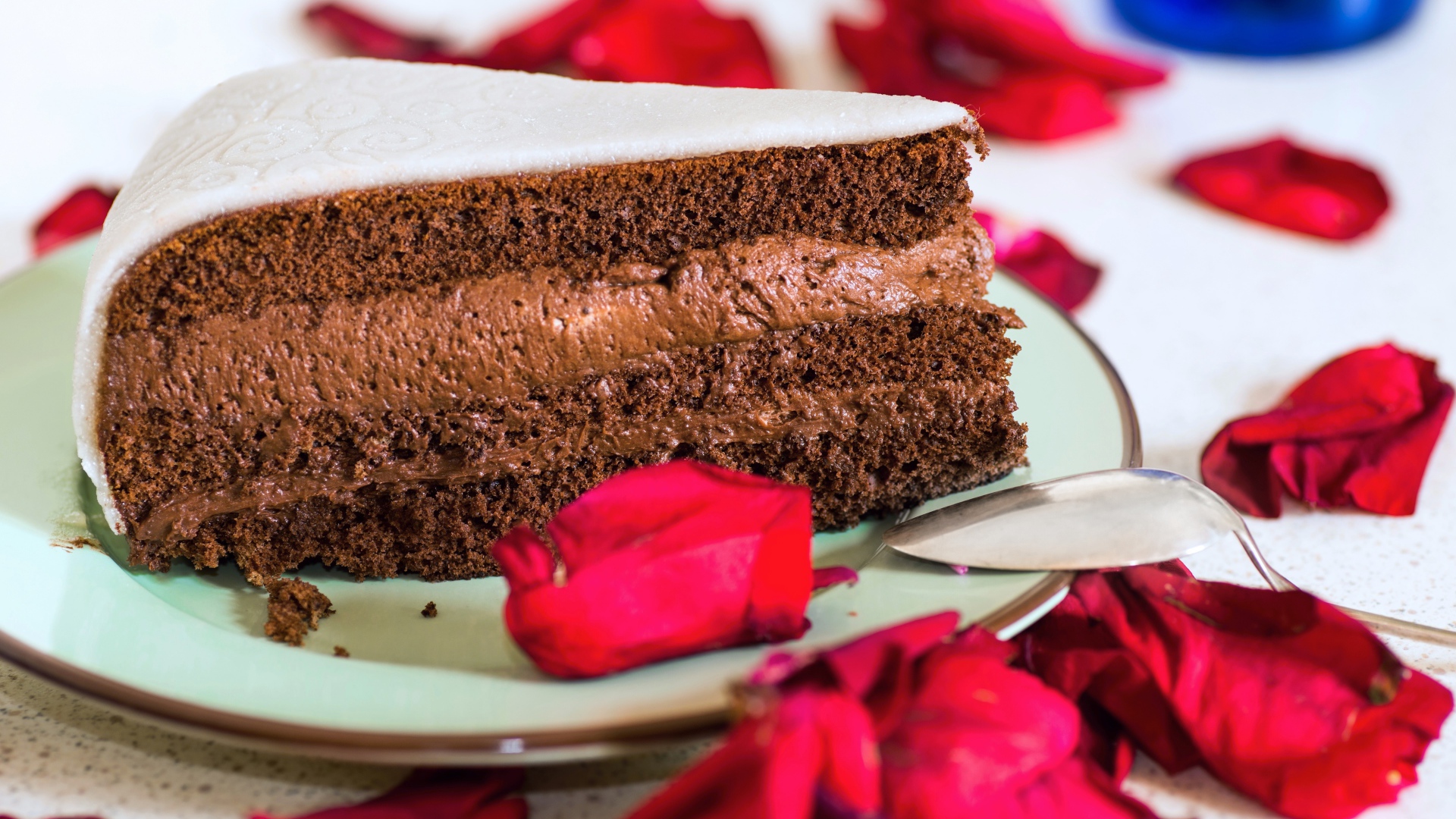 Кусок торта с шоколадным кремом и красными лепестками розы